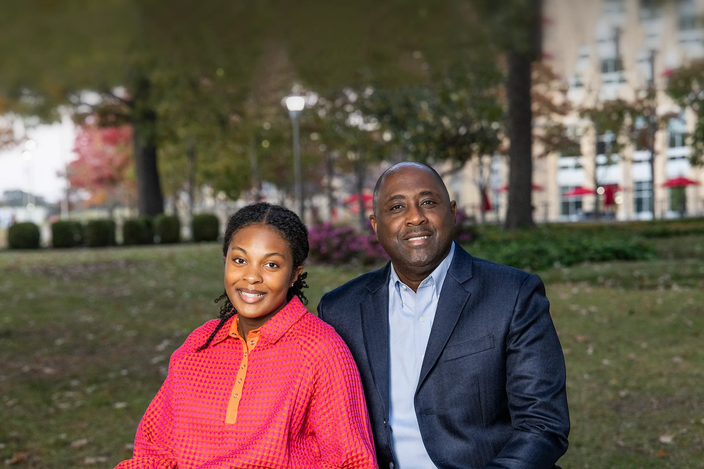 Dr. Calvin White and his daughter Monroe sit on a bench in the campus core.