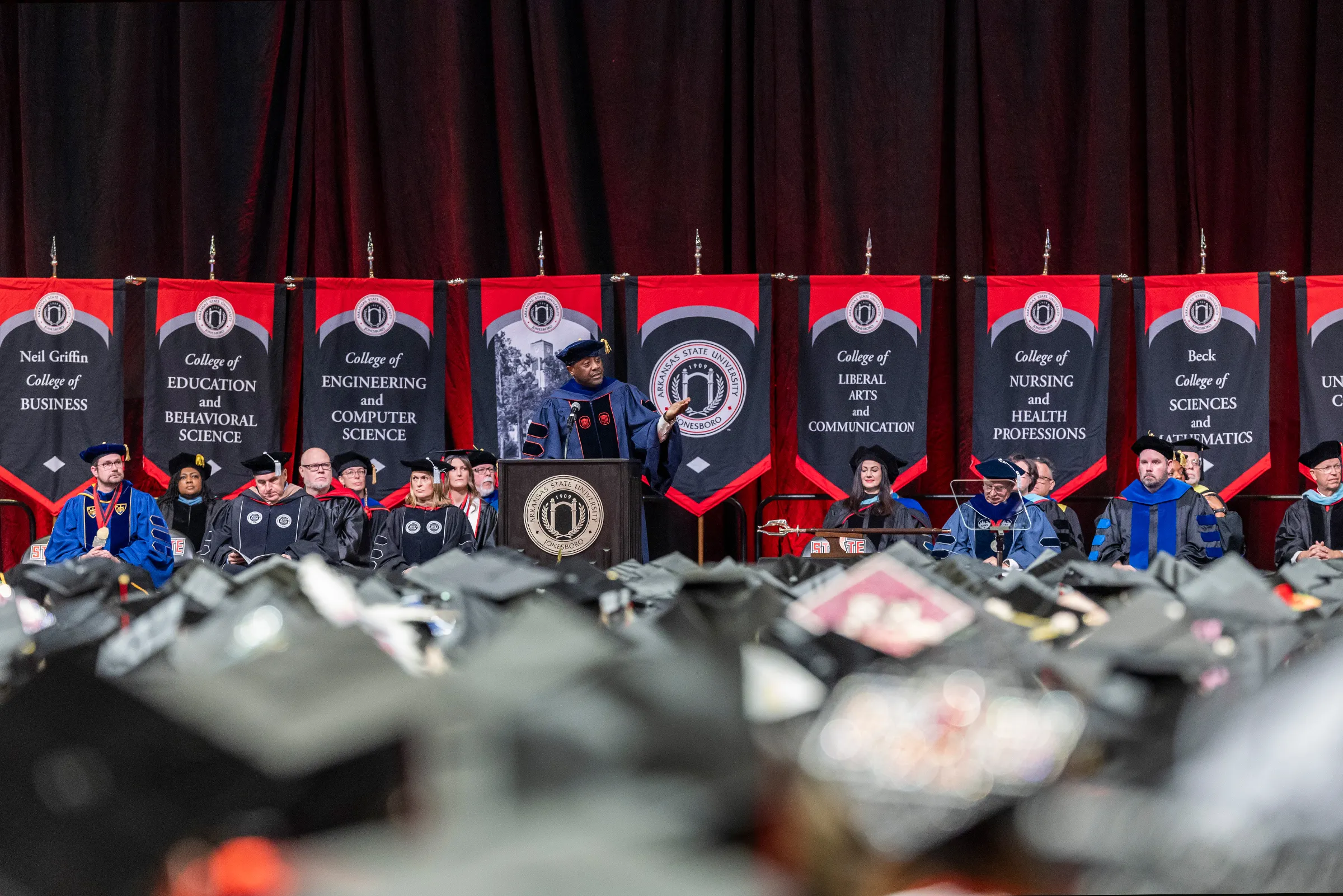 The A-State leadership team and Board of Trustees sit on the stage at a recent commencement ceremony.