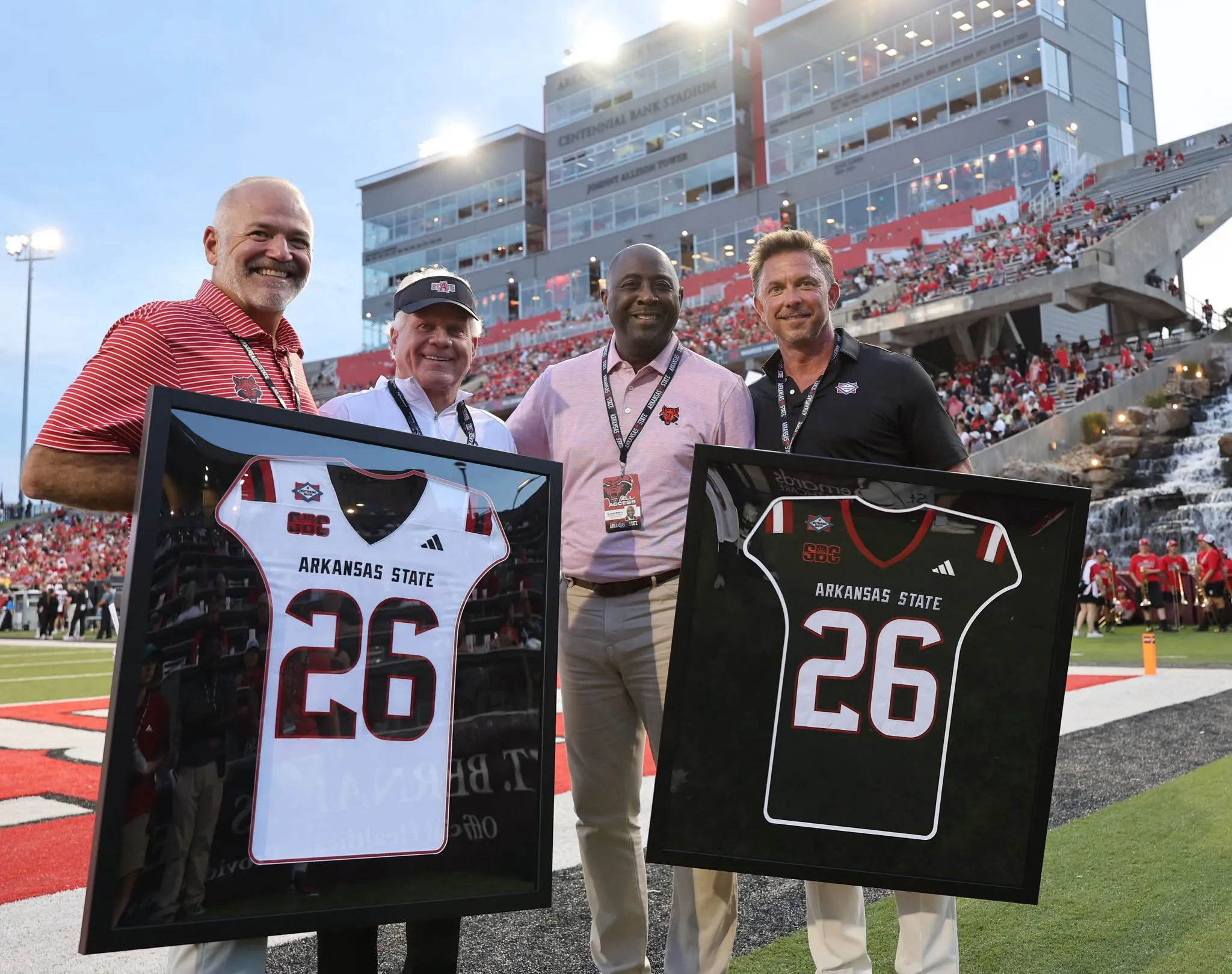 Dr. Calvin White poses with Centennial Bank leaders on the field at Centennial Bank Stadium during an A-State football game.