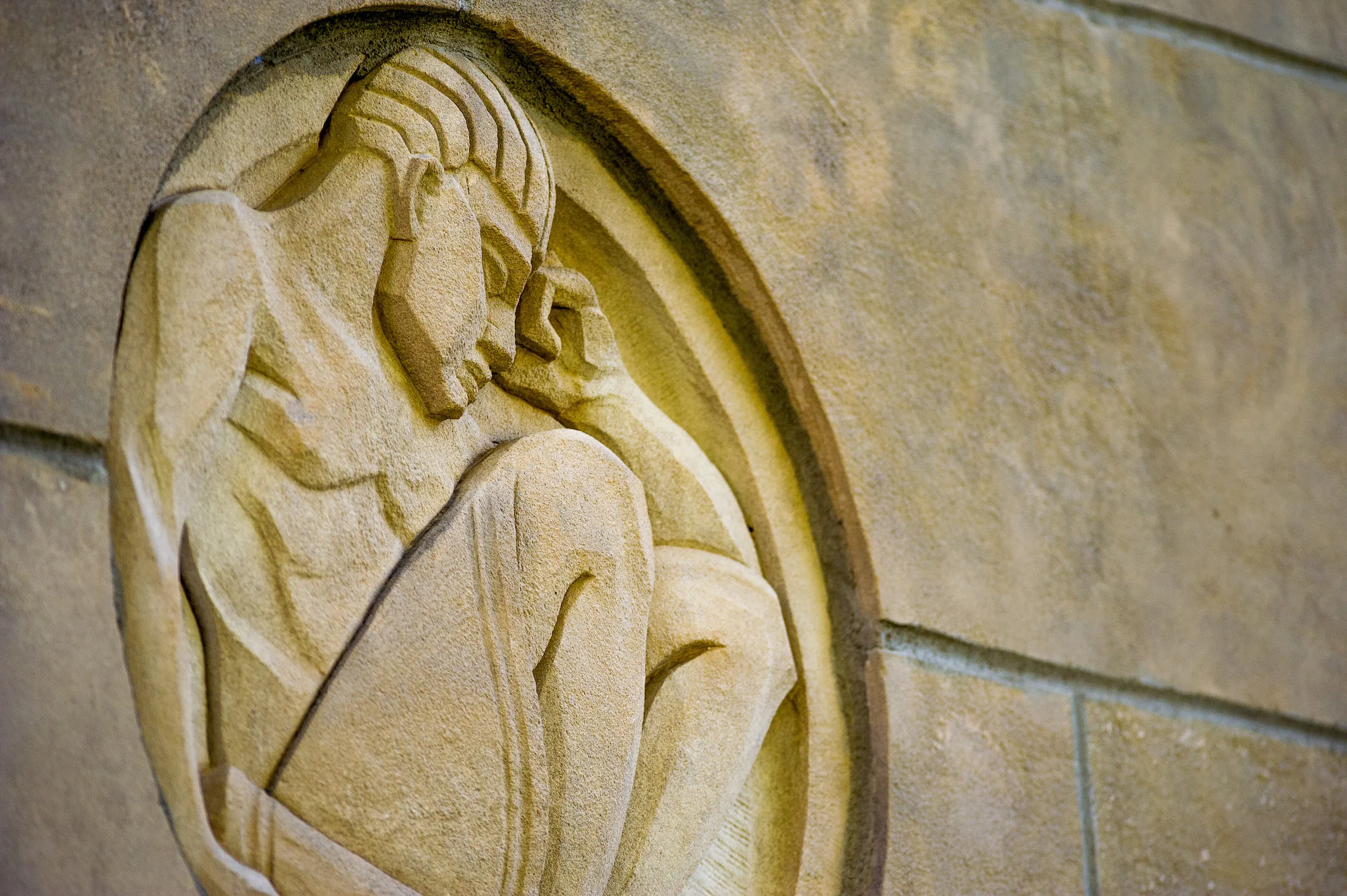 A background of The Scholar, carved in the side of Wilson Hall