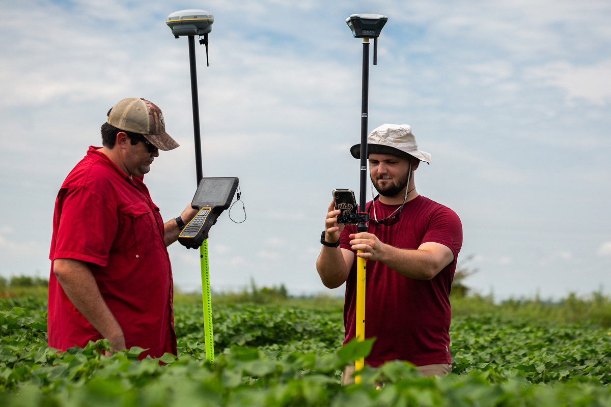 Two students using a GPS device in a field.