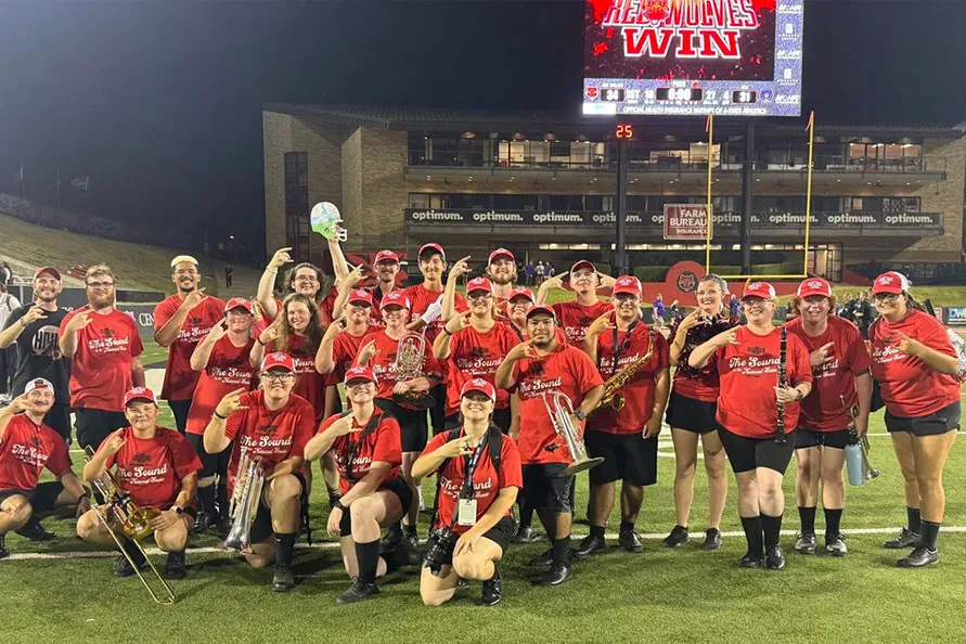 A group of band members making the TBS hand gesture