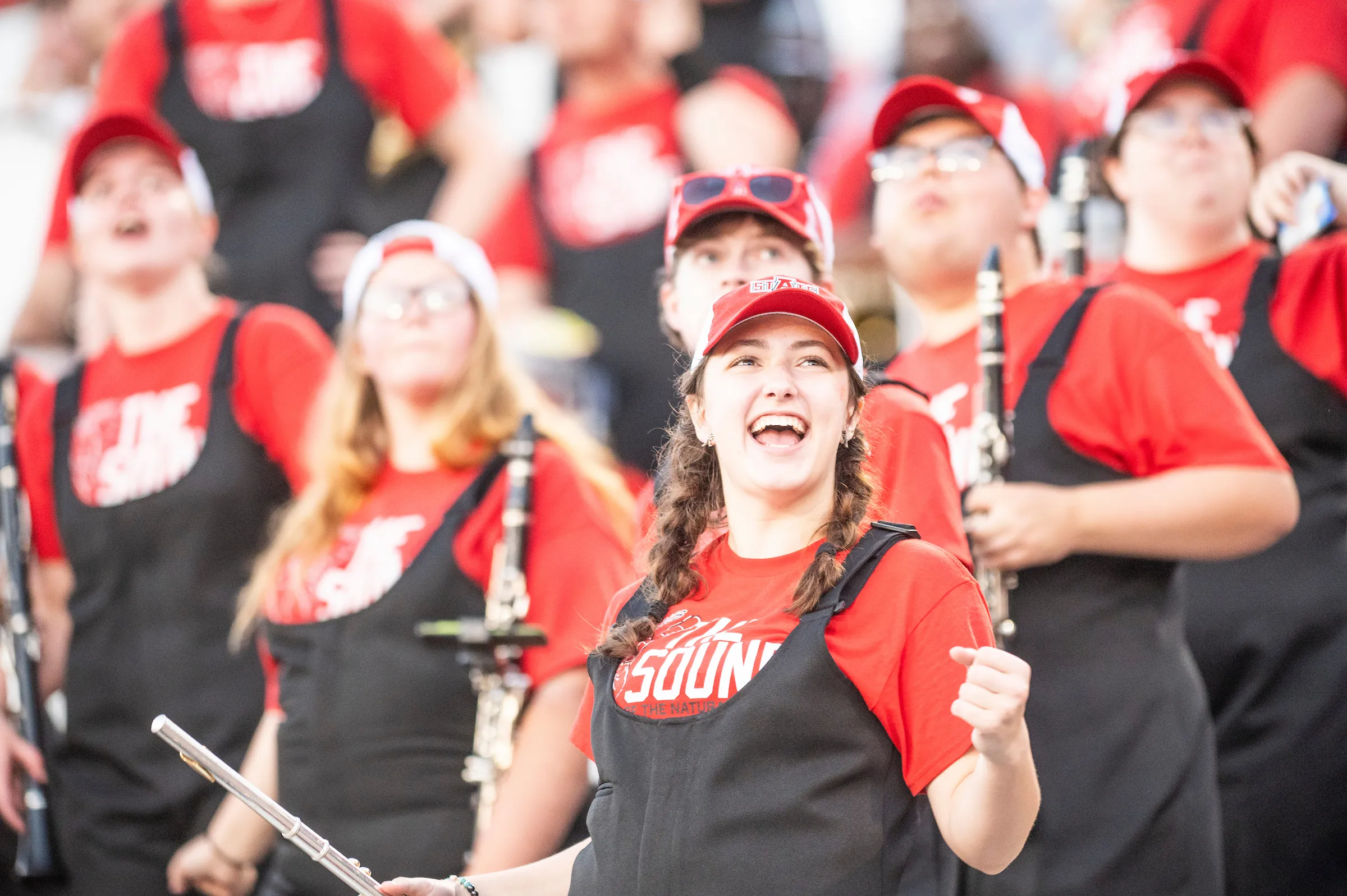 A female band members smiles during a performance at Centennial Bank Stadium