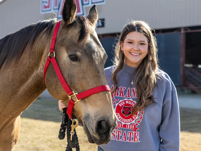 A pre-vet student poses with a horse