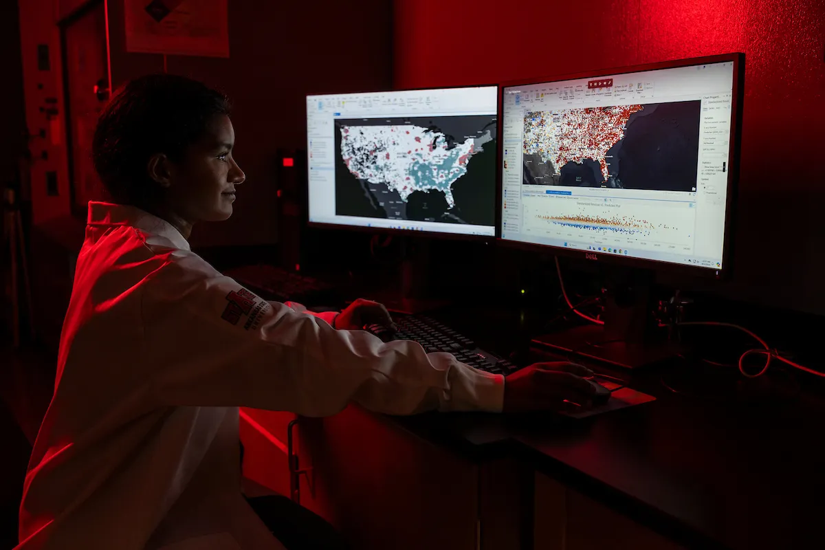 A student looking at dual computer screens with population data