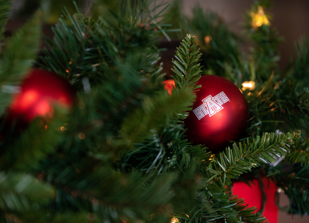 A red A-State ornament in a Christmas tree