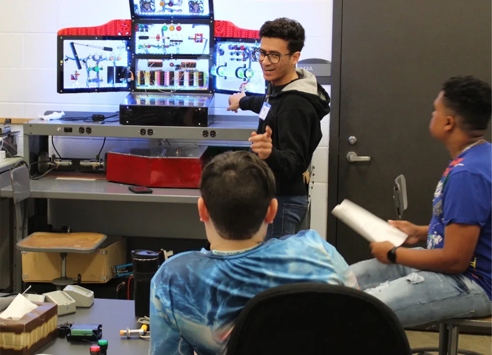 Teacher showing summer camp students an engineering project.