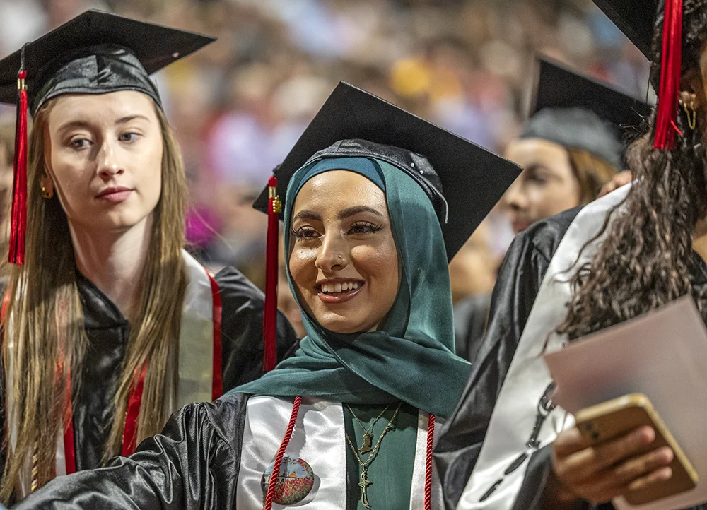 Graduate in hijab smiling at commencement.