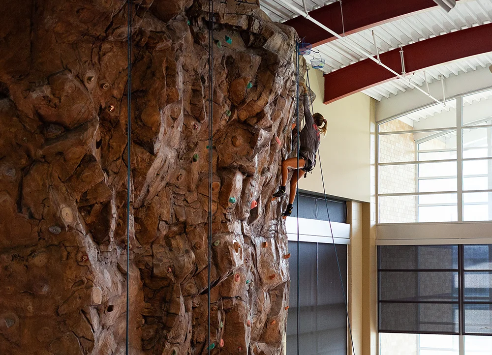 A student climbing on the climbing wall.
