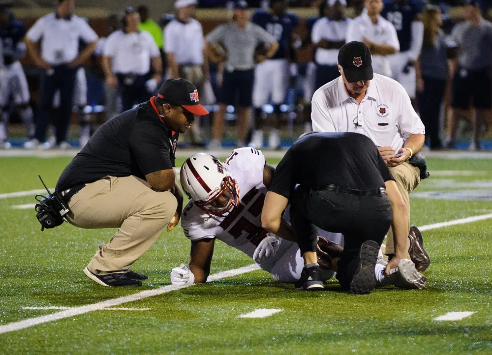 Athletic trainer on the field helping injured football player.