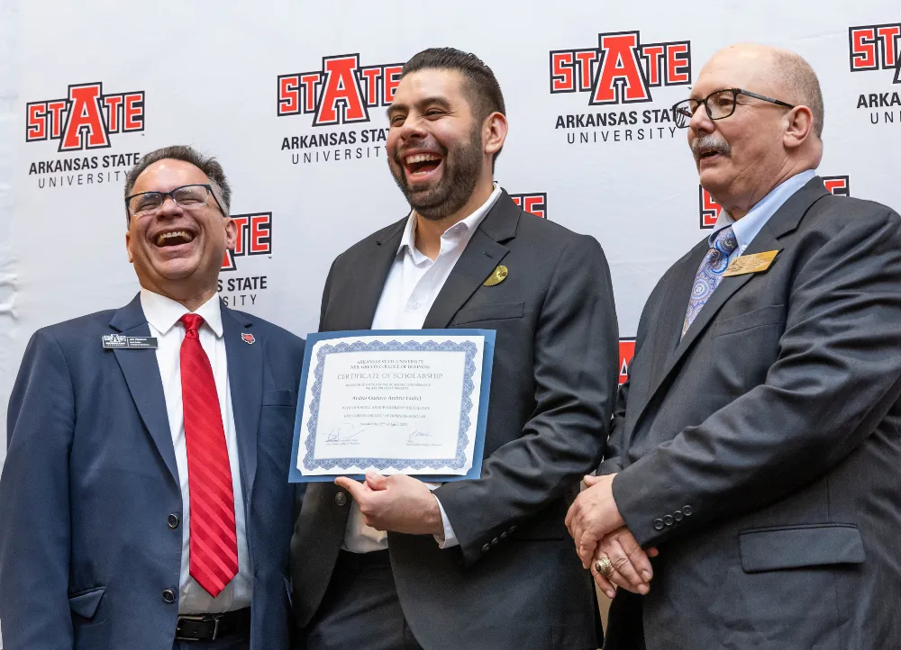 A student in a suit receiving a scholarship.
