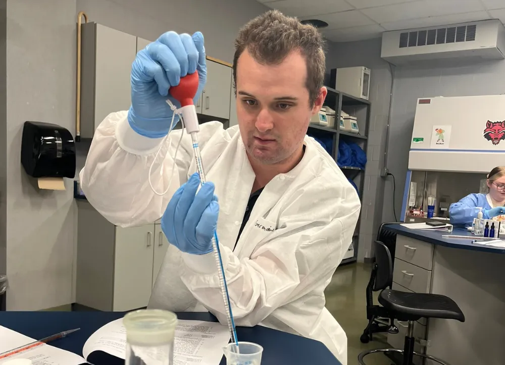 Clinical Lab student measuring liquids and analyzing it.
