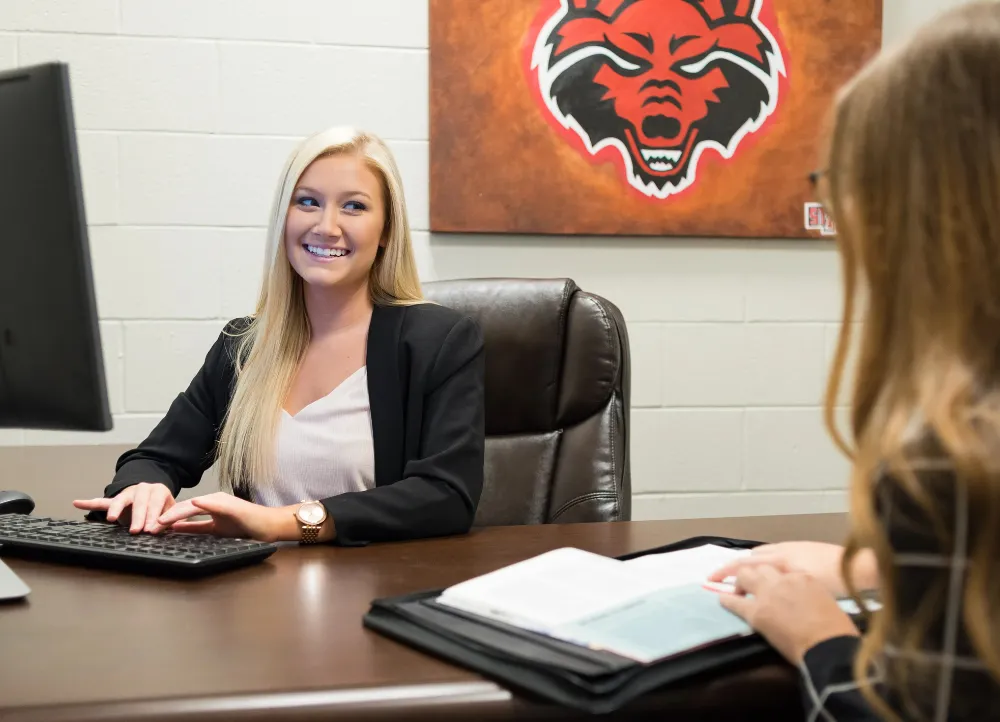 Student being interviewed at a desk.