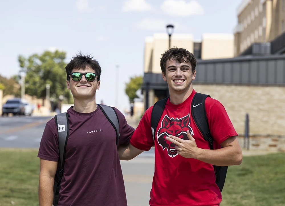 Two students in Red Wolves gear smile and pose together.