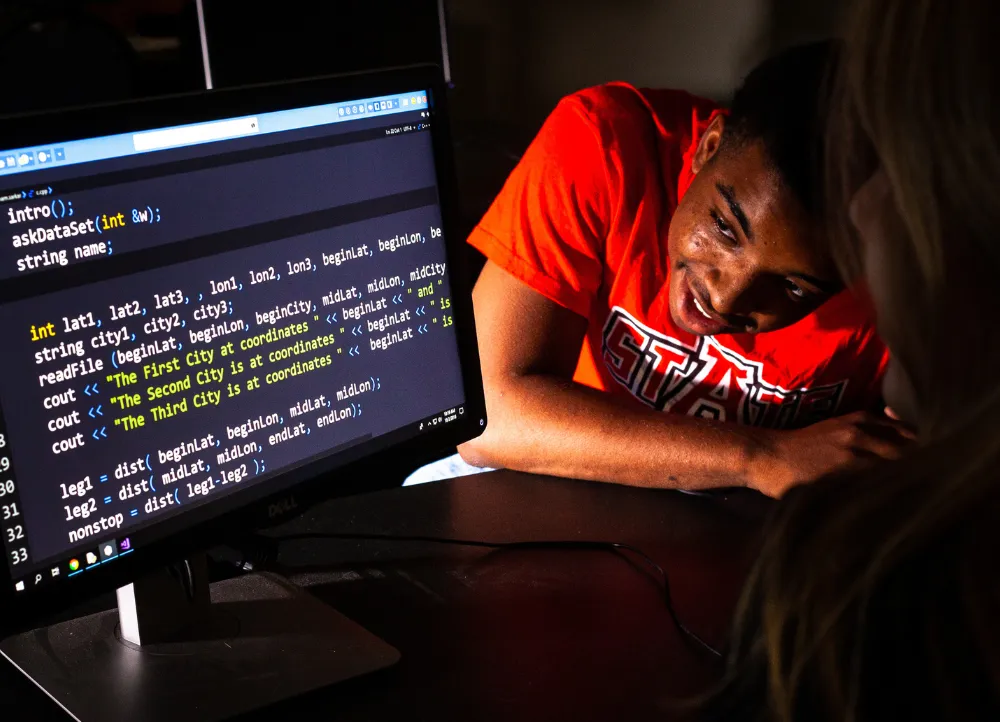 Two students looking at coding work in computer science.