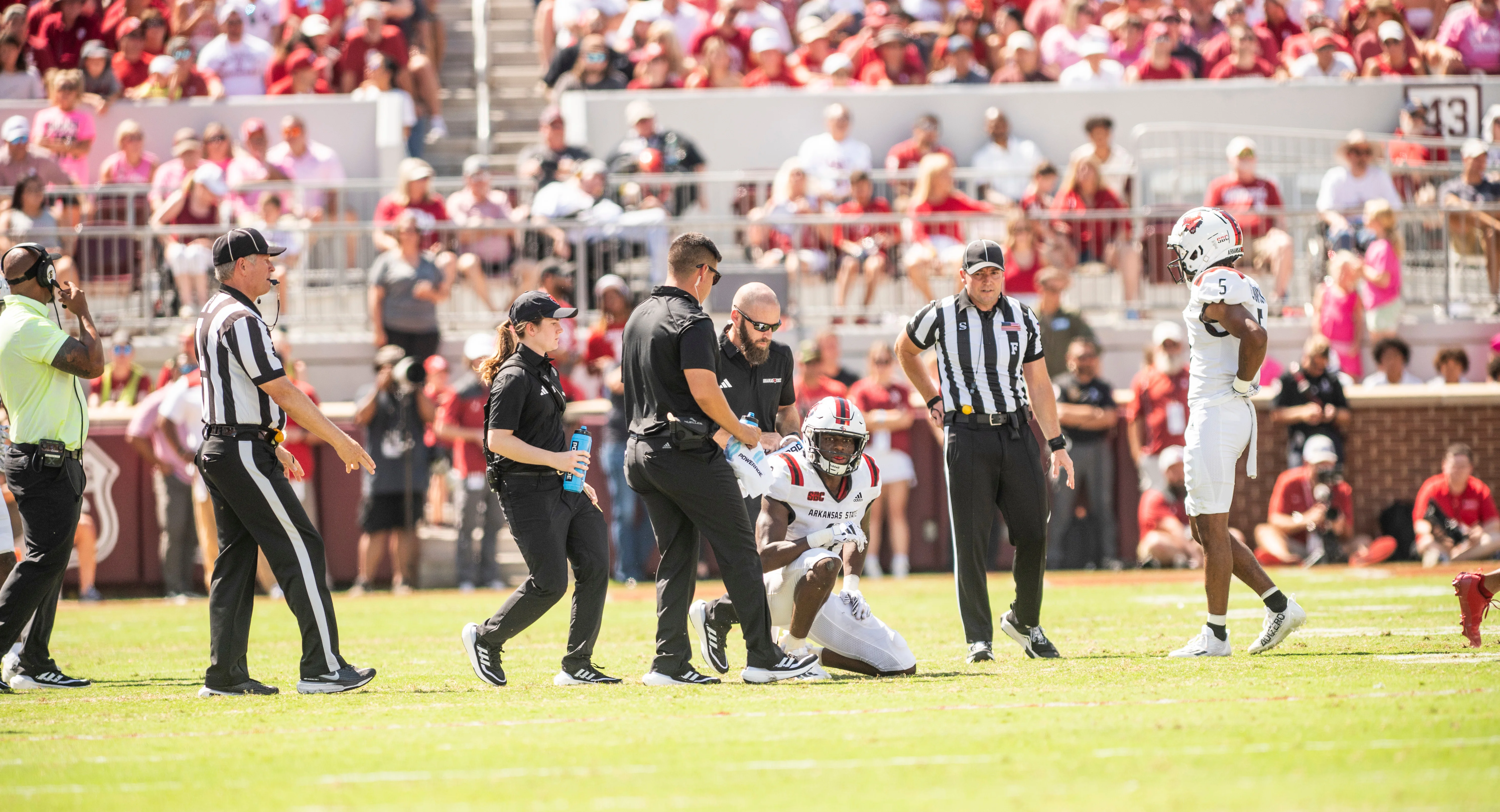 Athletic trainers helping redwolf football player off the field after an injury.