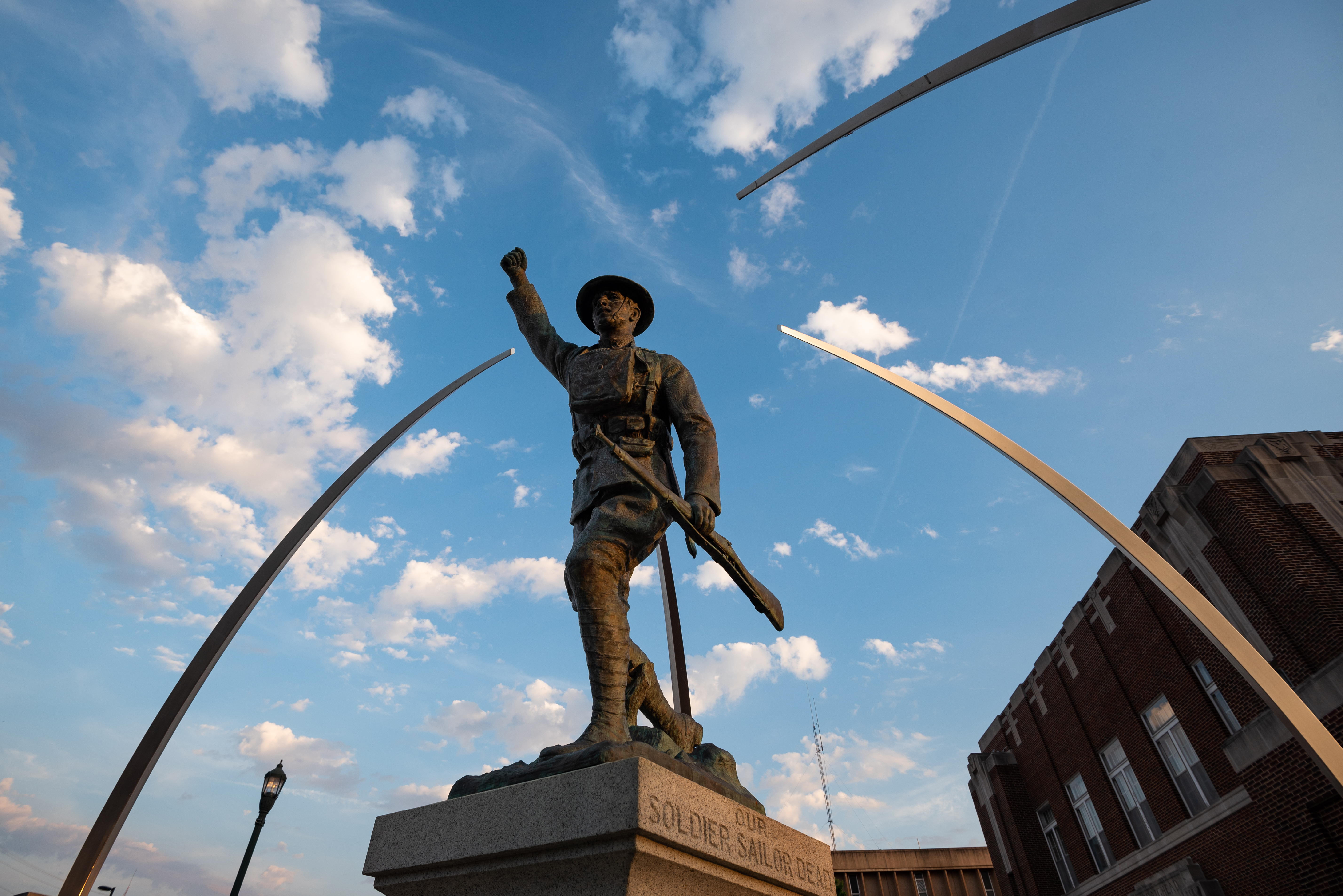 A view of a bronze statue from below with a blue sky in the background