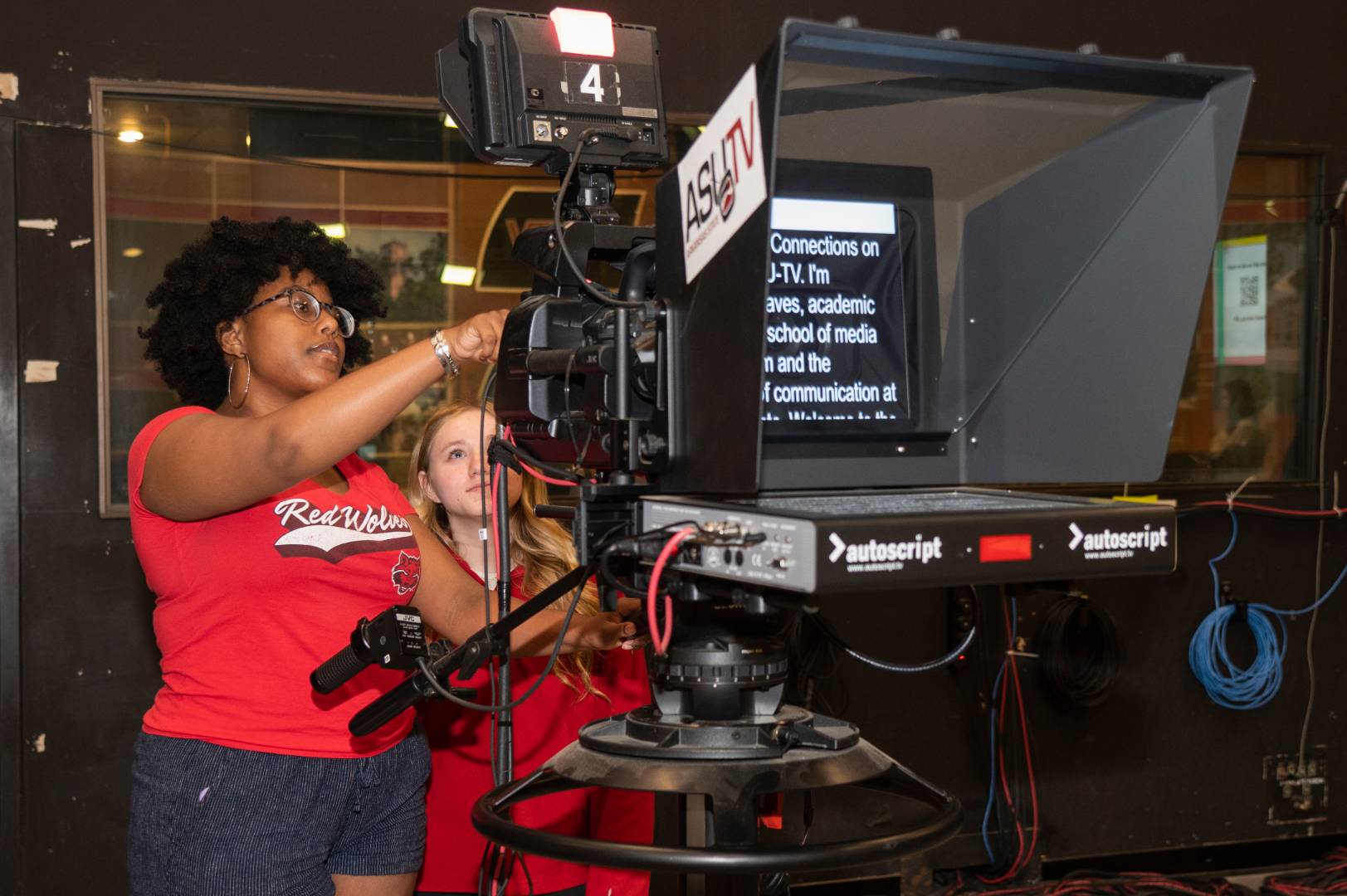 A student showing another student how to use a news camera.