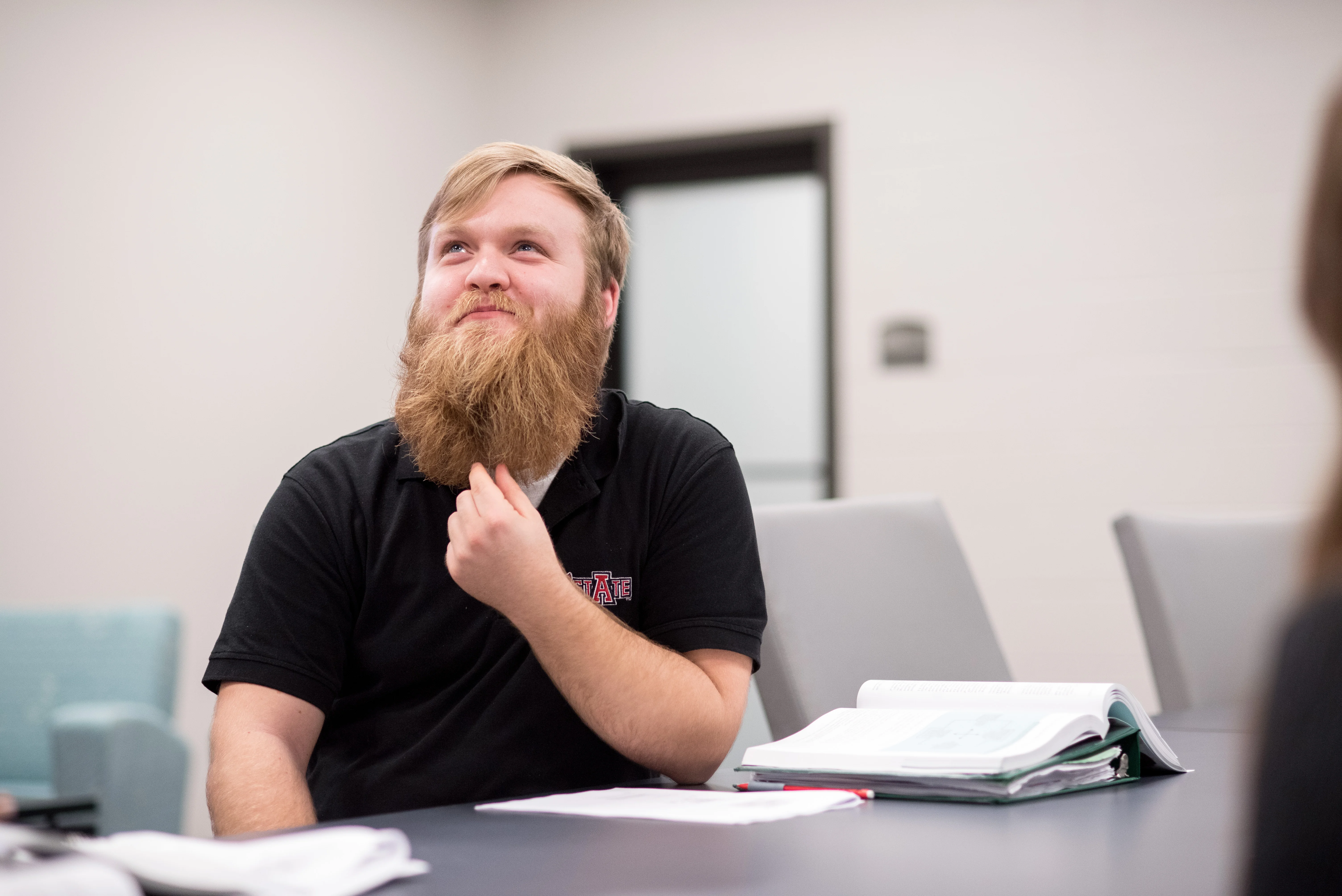 Business student thinking while stroking beard.