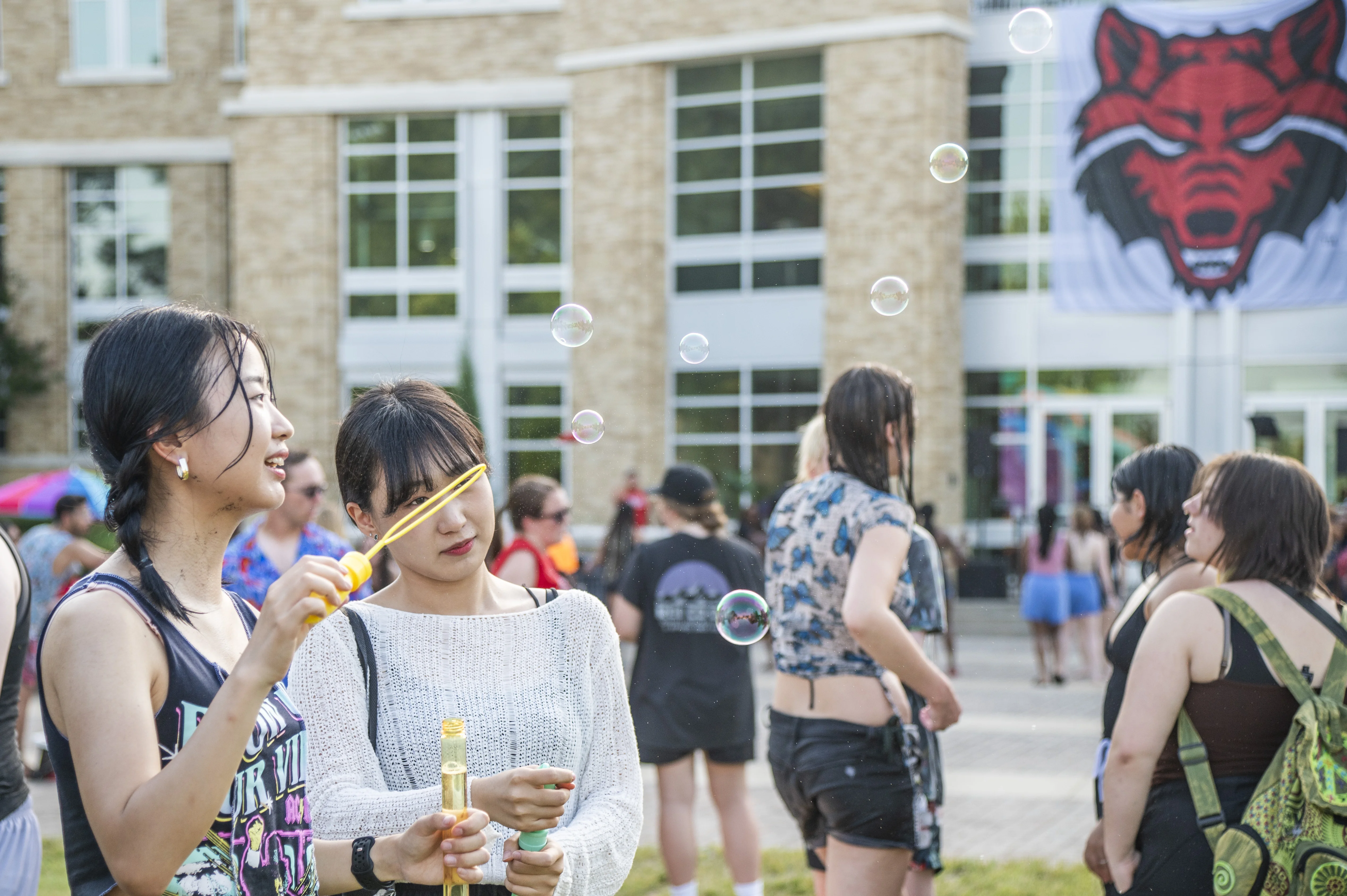 Students blowing bubble at a summer event outside of the student union.