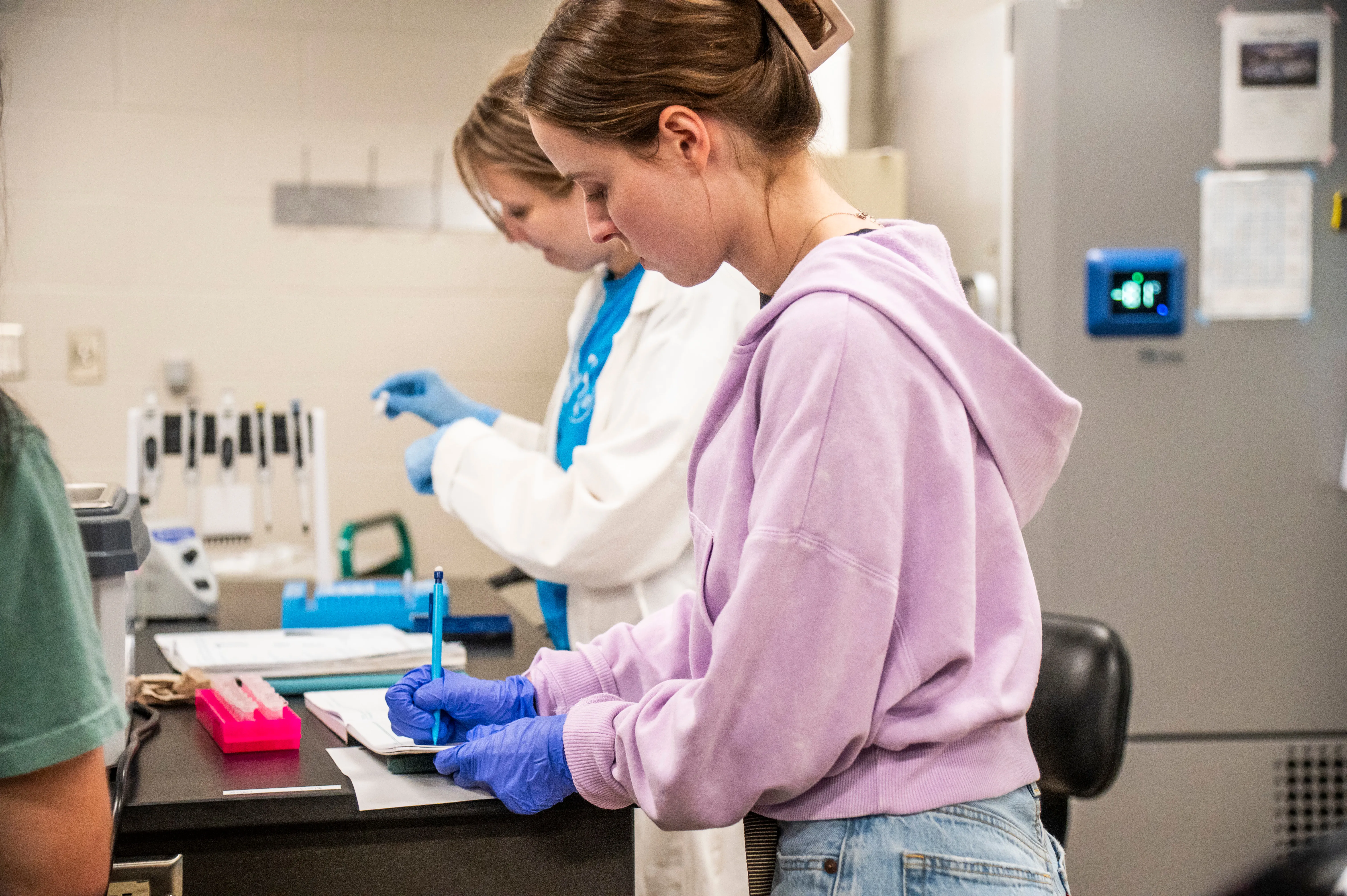 AState student doing analysis samples with test tubes in class and taking notes.