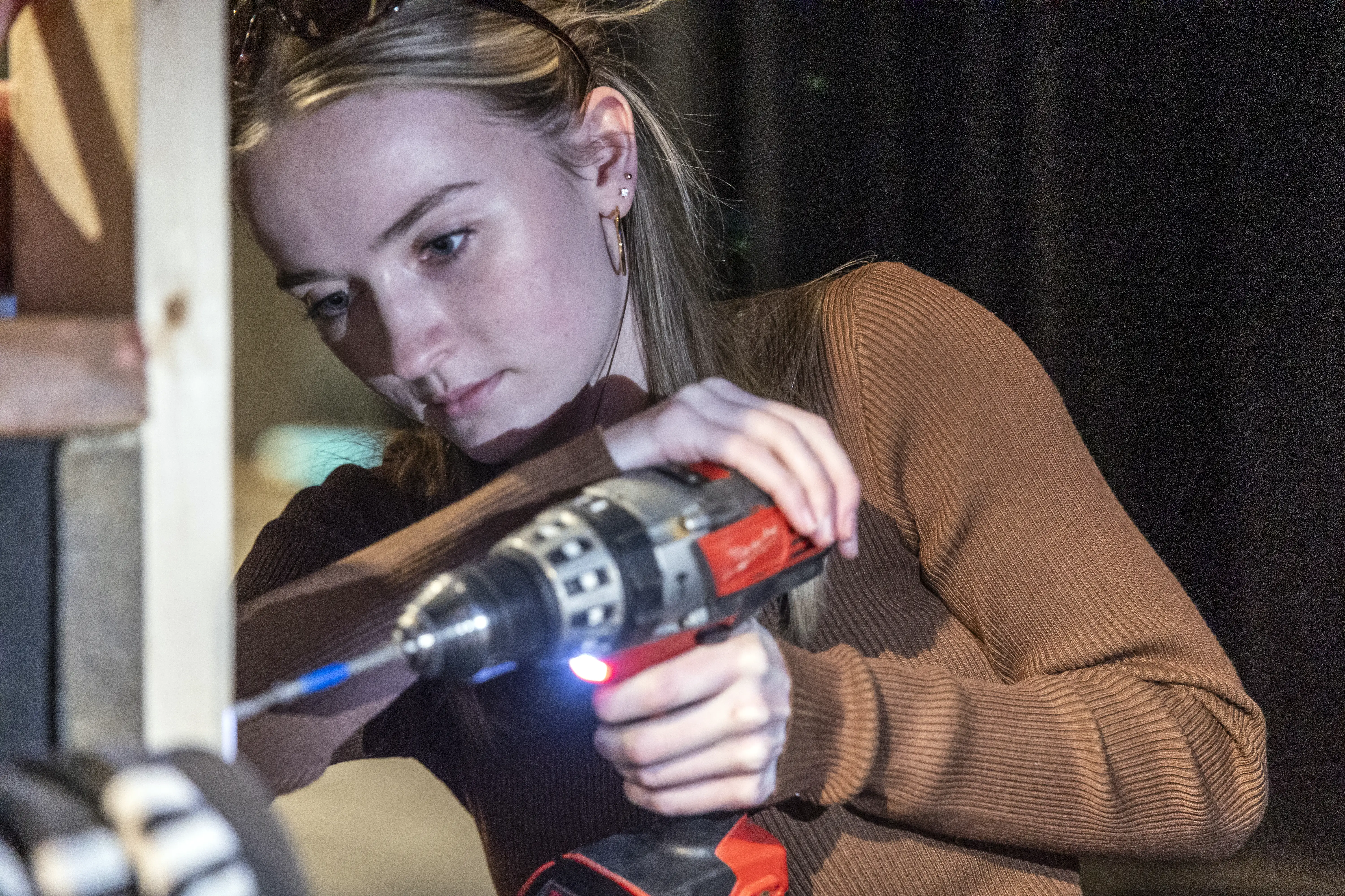 A student using a drill on a set.