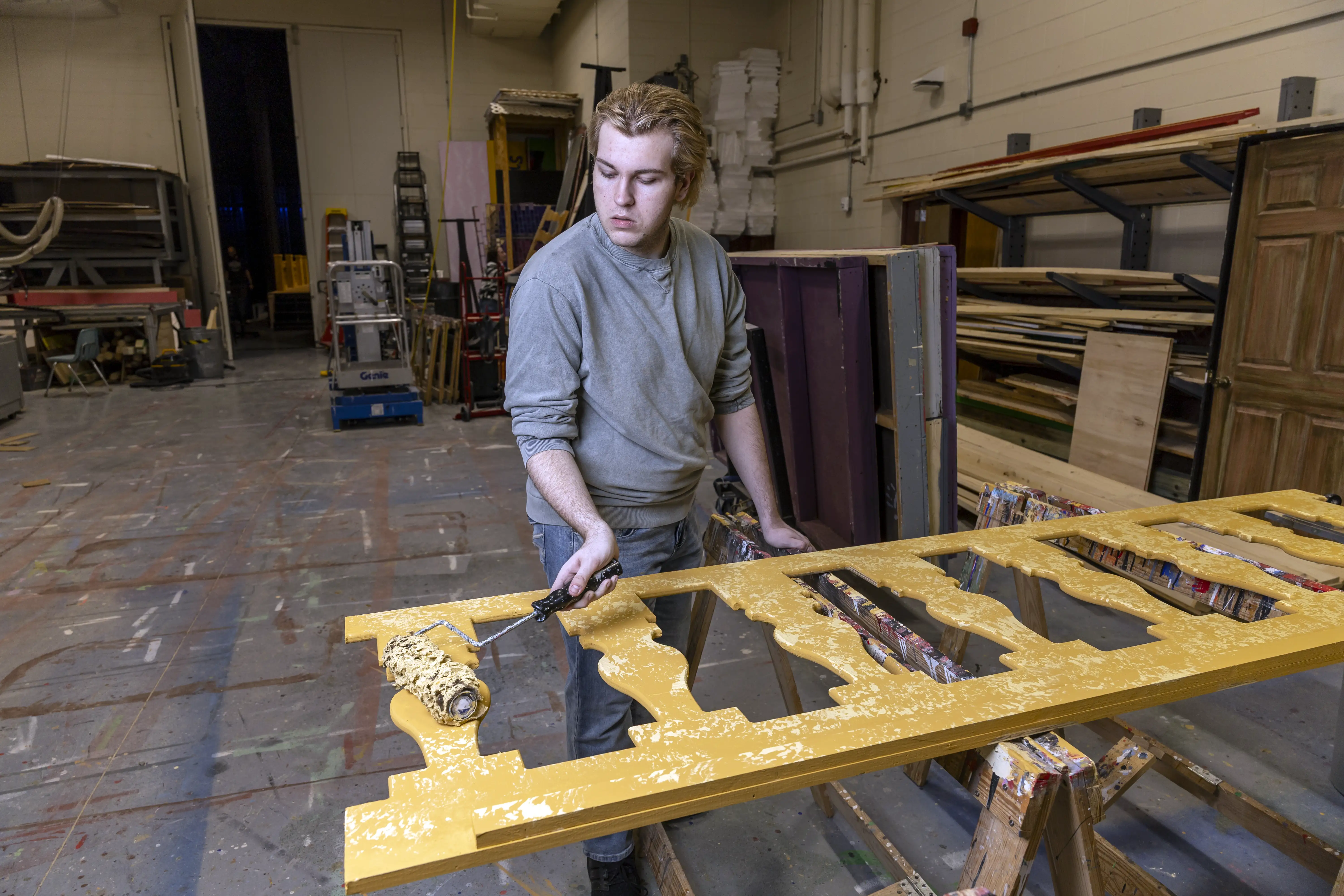 A student painting a wooden prop.