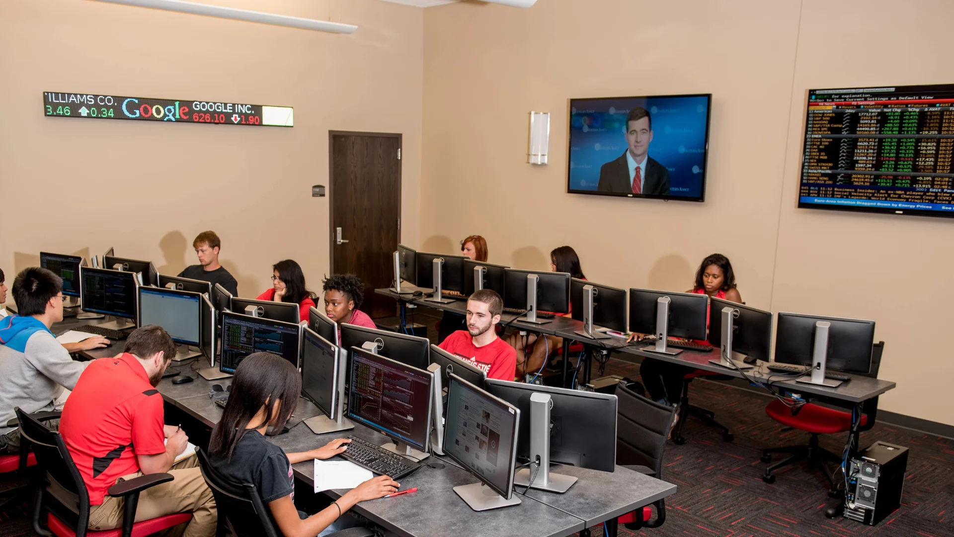 A-State Dawson Capitol room with teacher speaking to students as they watch stock prices fluctuate in real time.