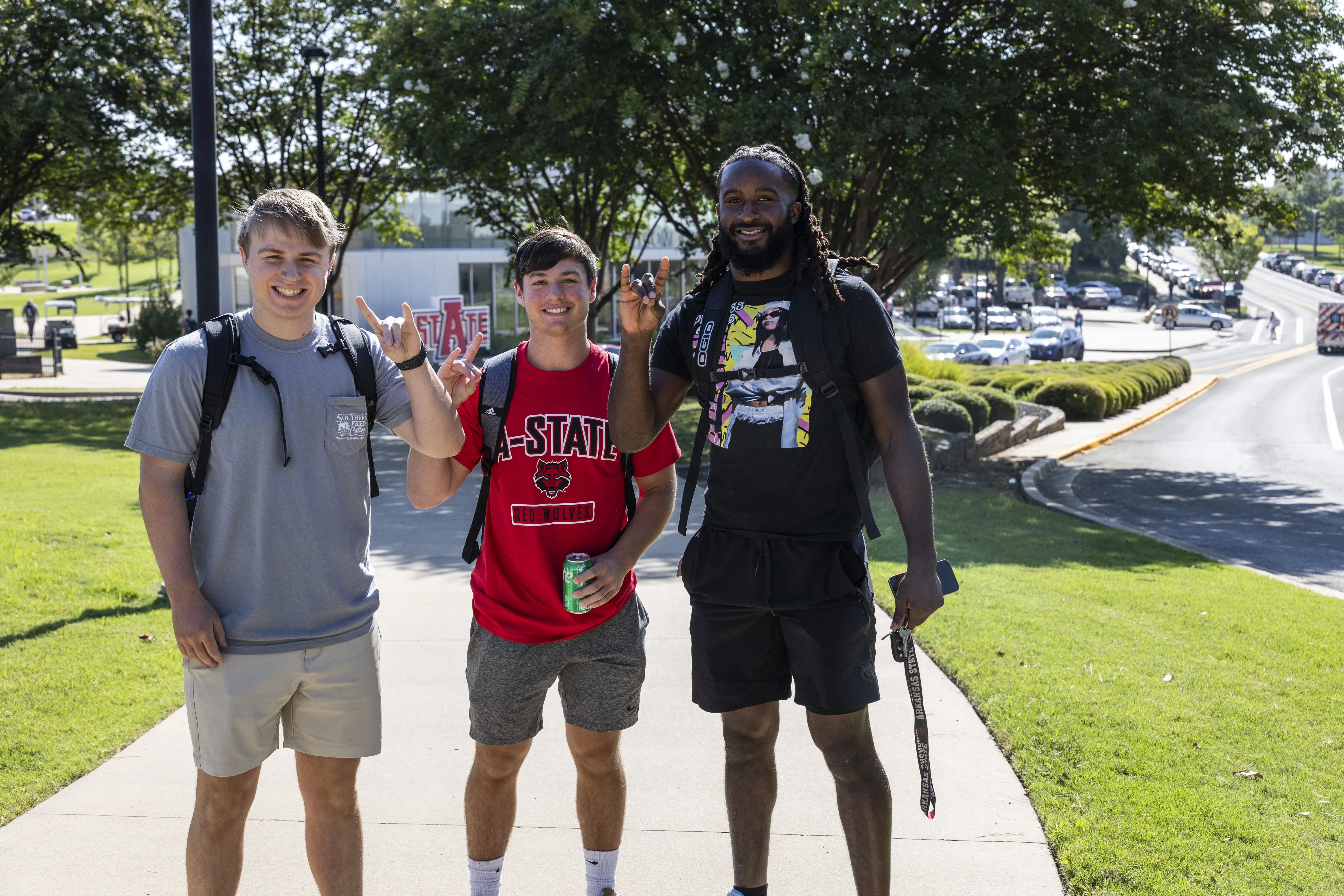 Three A-State students on their first day of class giving the wolves up sign.