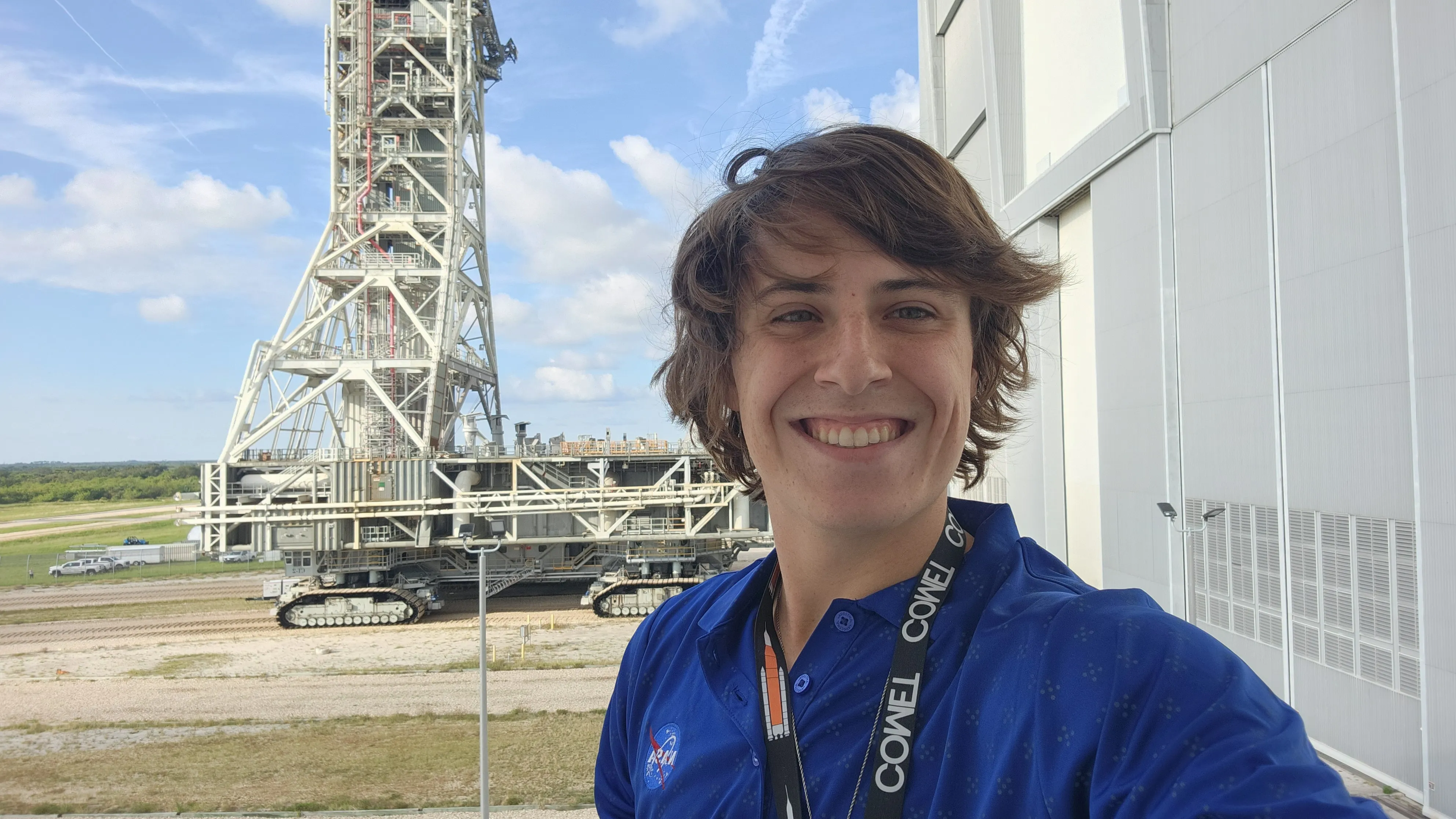 Mason Rhodes outside of NASA at work with a rocket in the background