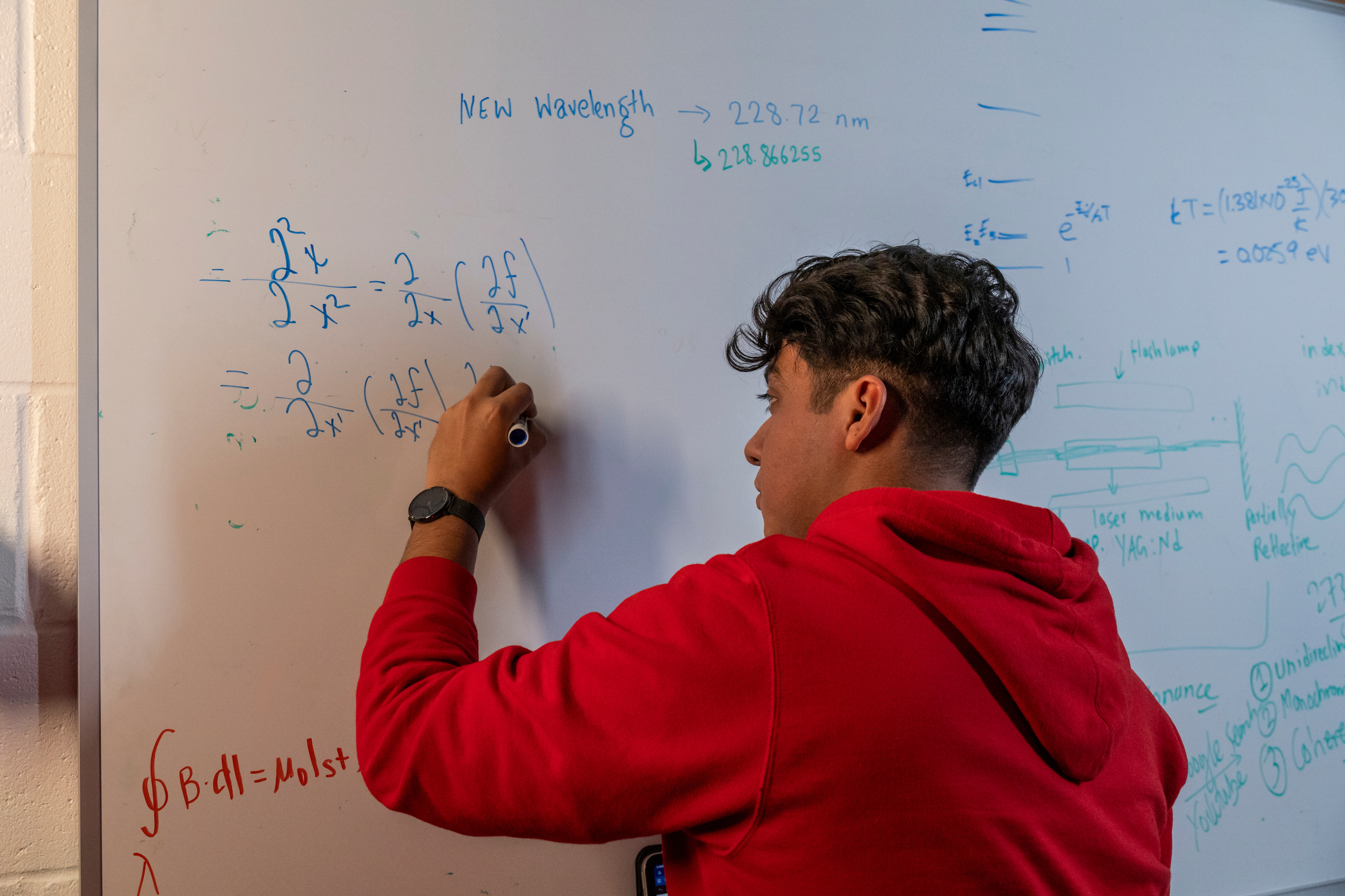 A student doing math problems on a whiteboard.