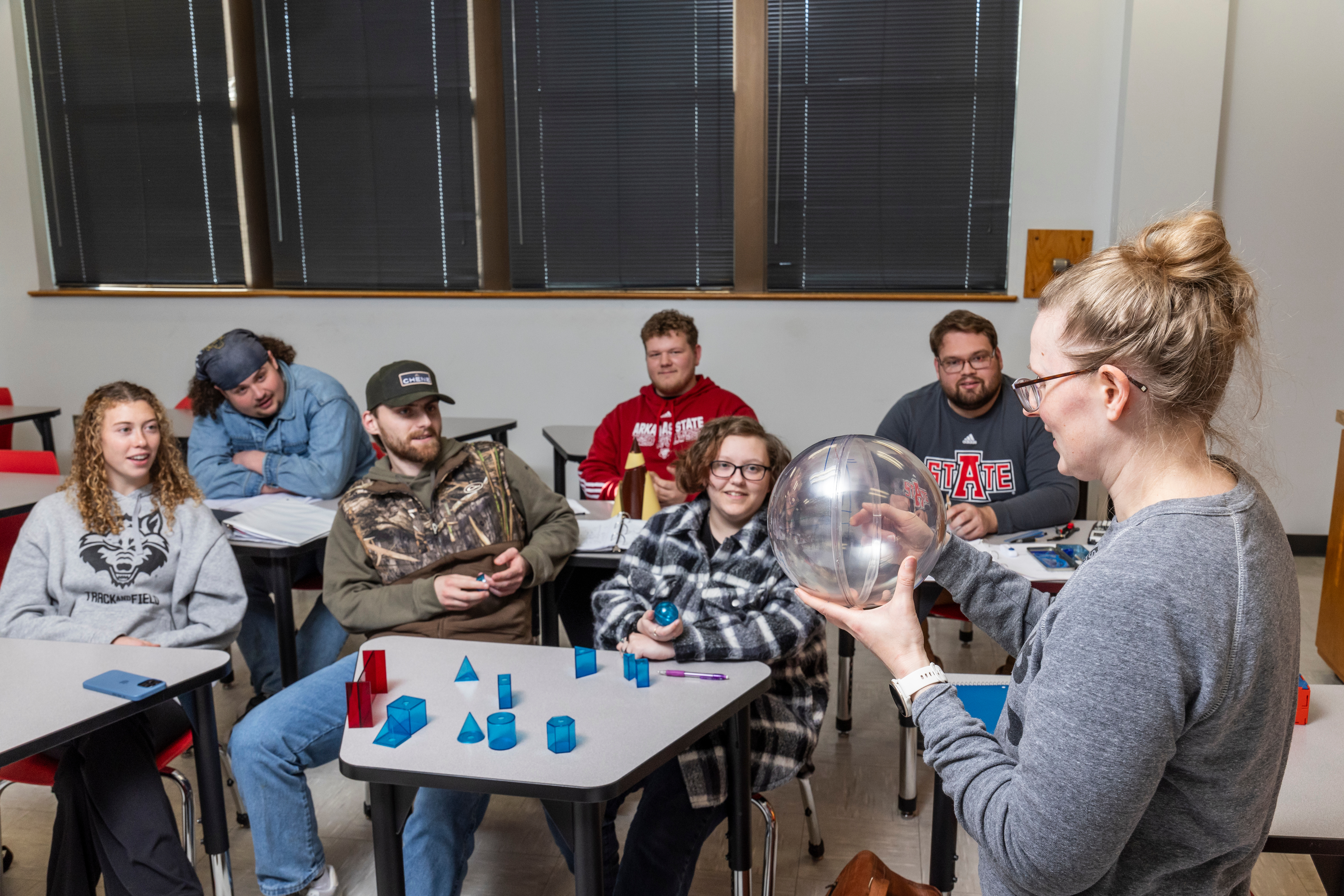 A professor giving a demonstration to the class using a 3D sphere.