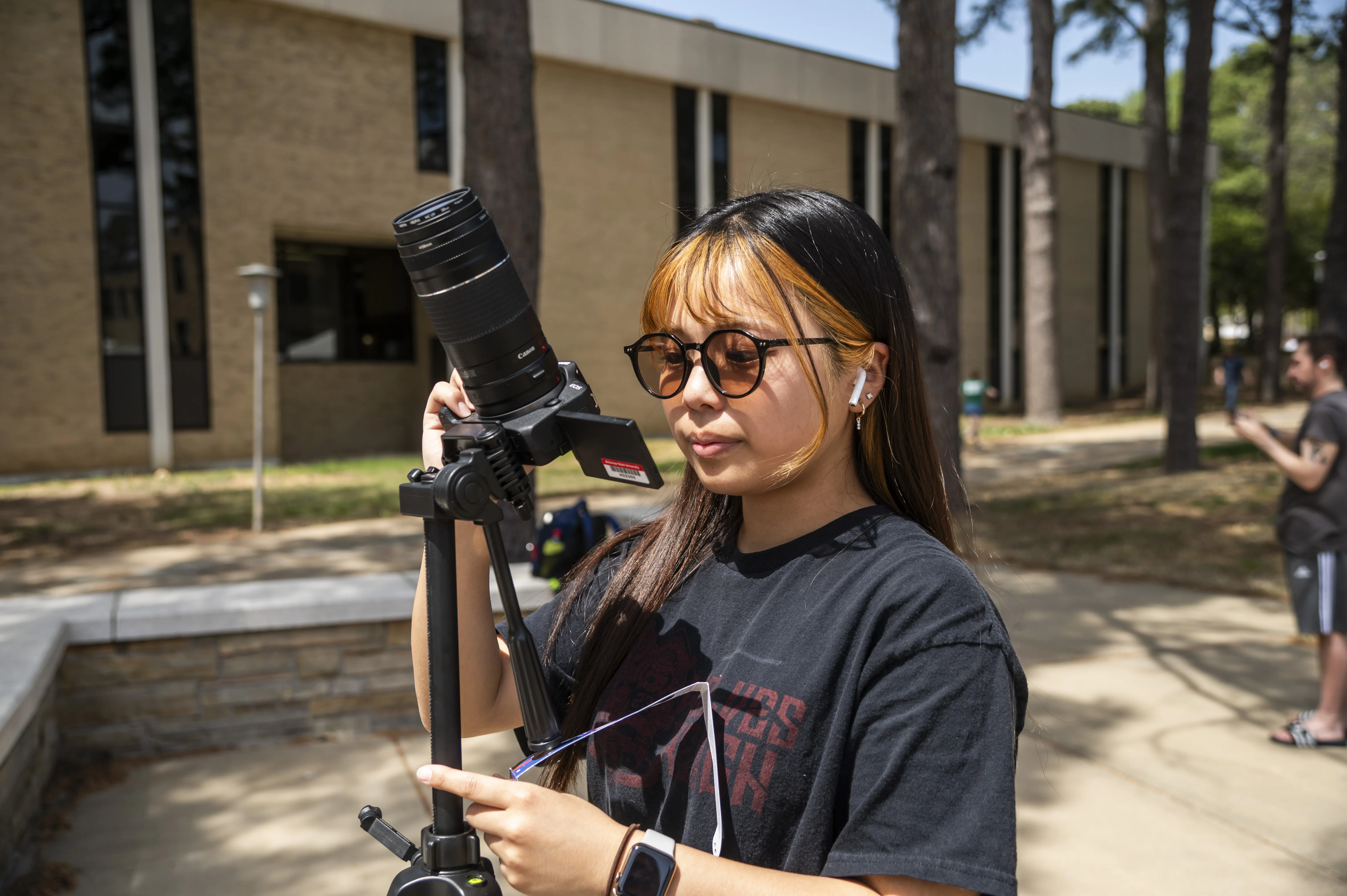 A student preparing to film for an outdoors shot on campus.