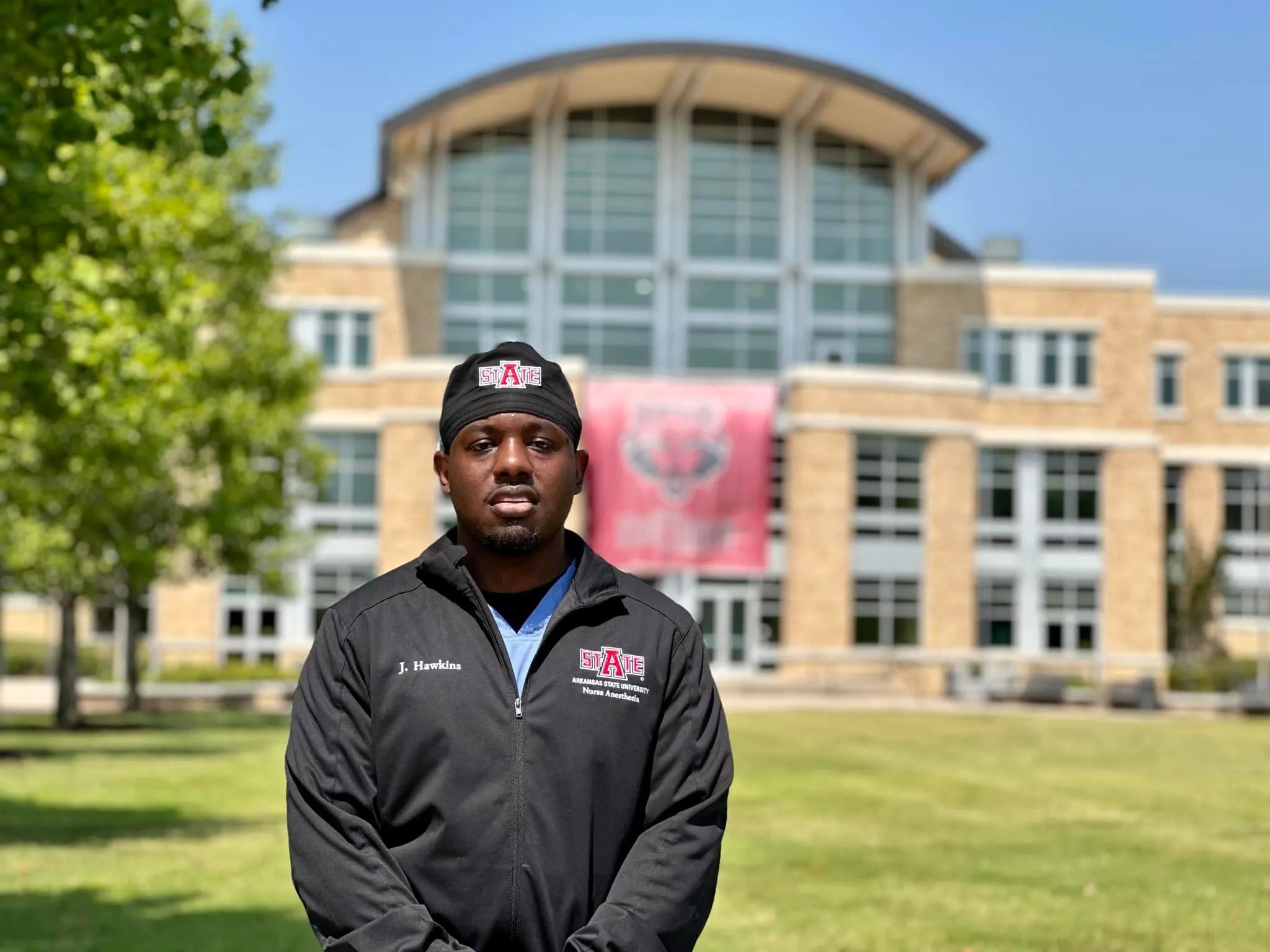 DNP student posing outside of the student union in an A-State Nurse Anesthesia coat.