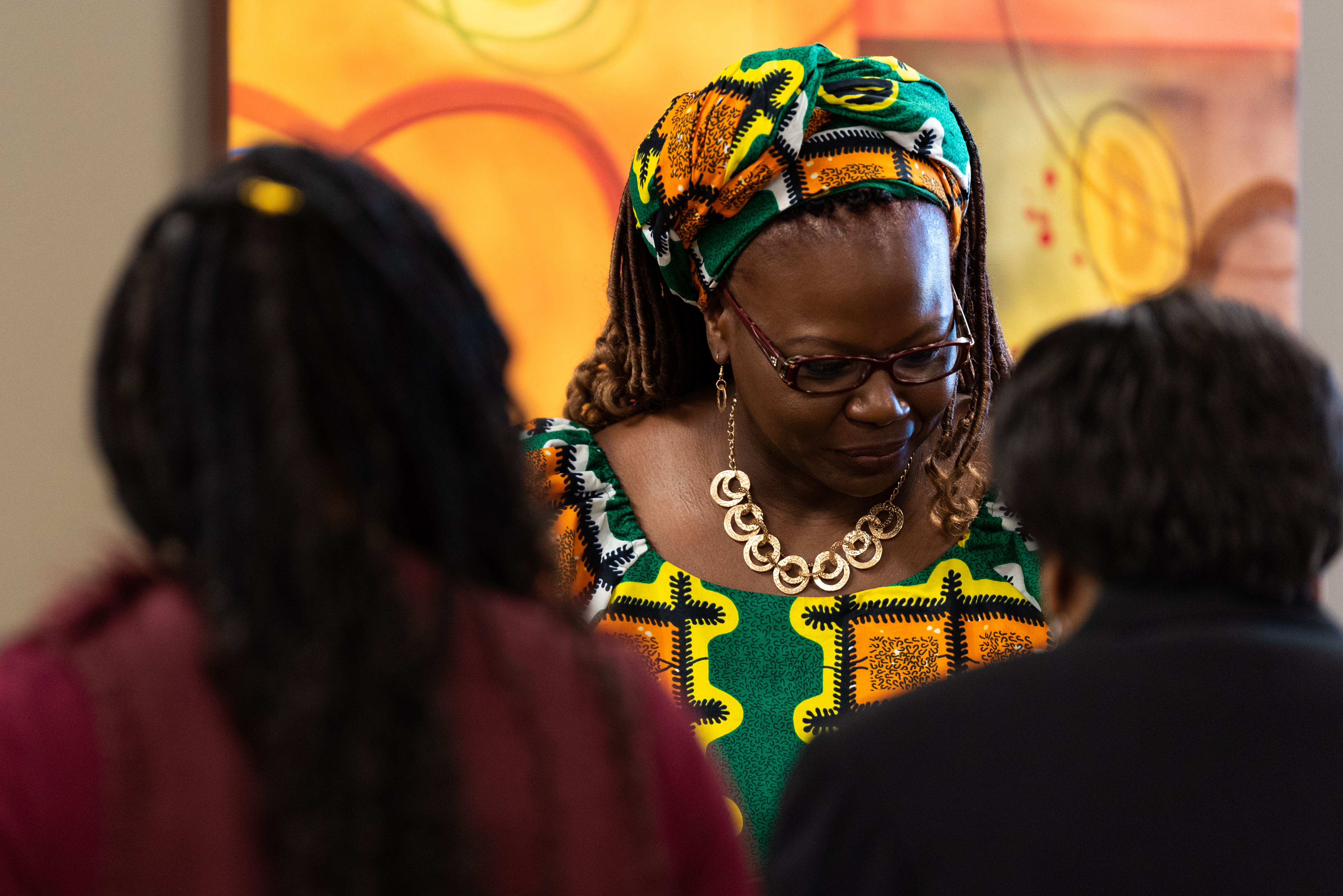 An African-American woman speaking to two people in the foreground