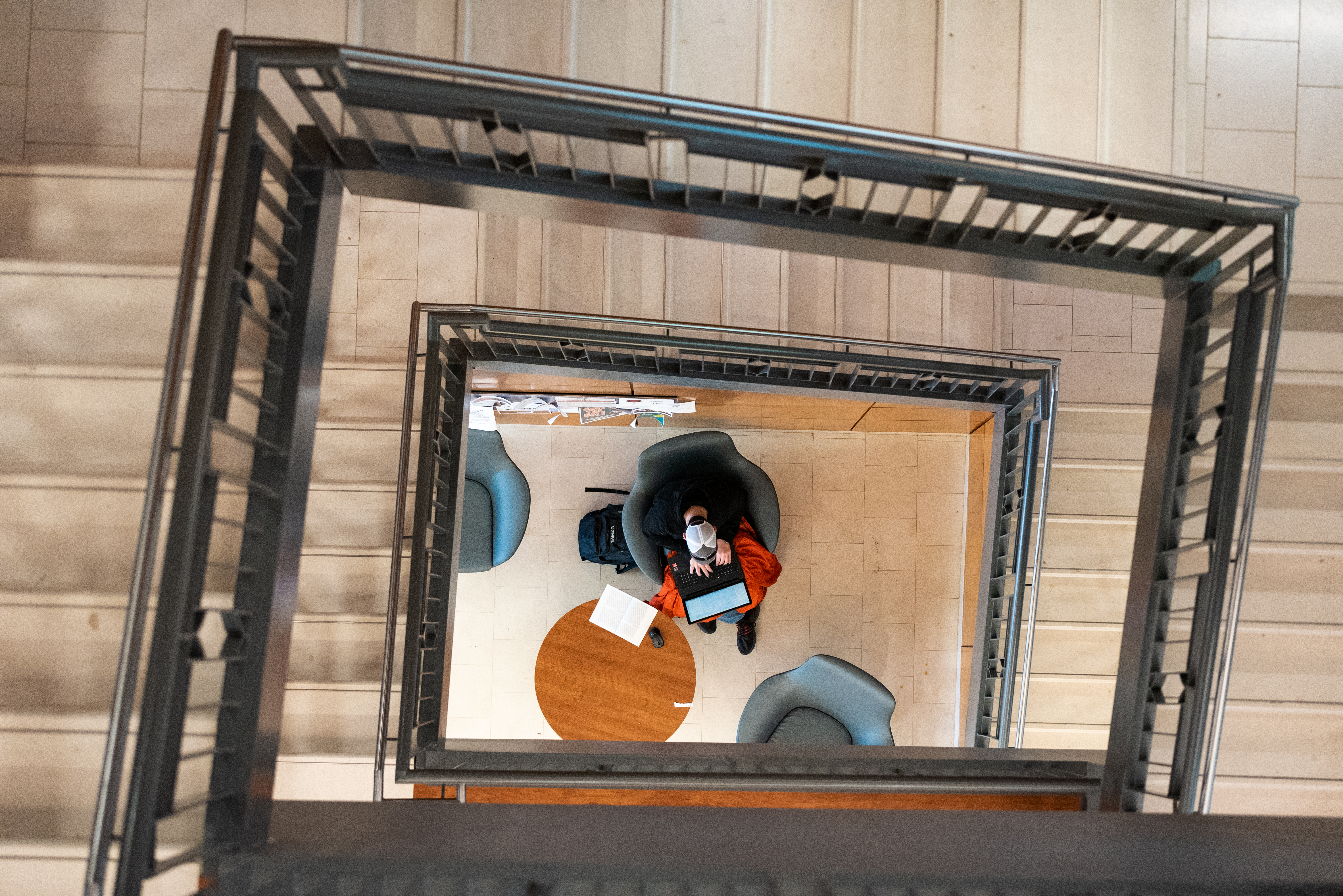 A photo looking down a staircase at a student studying below.