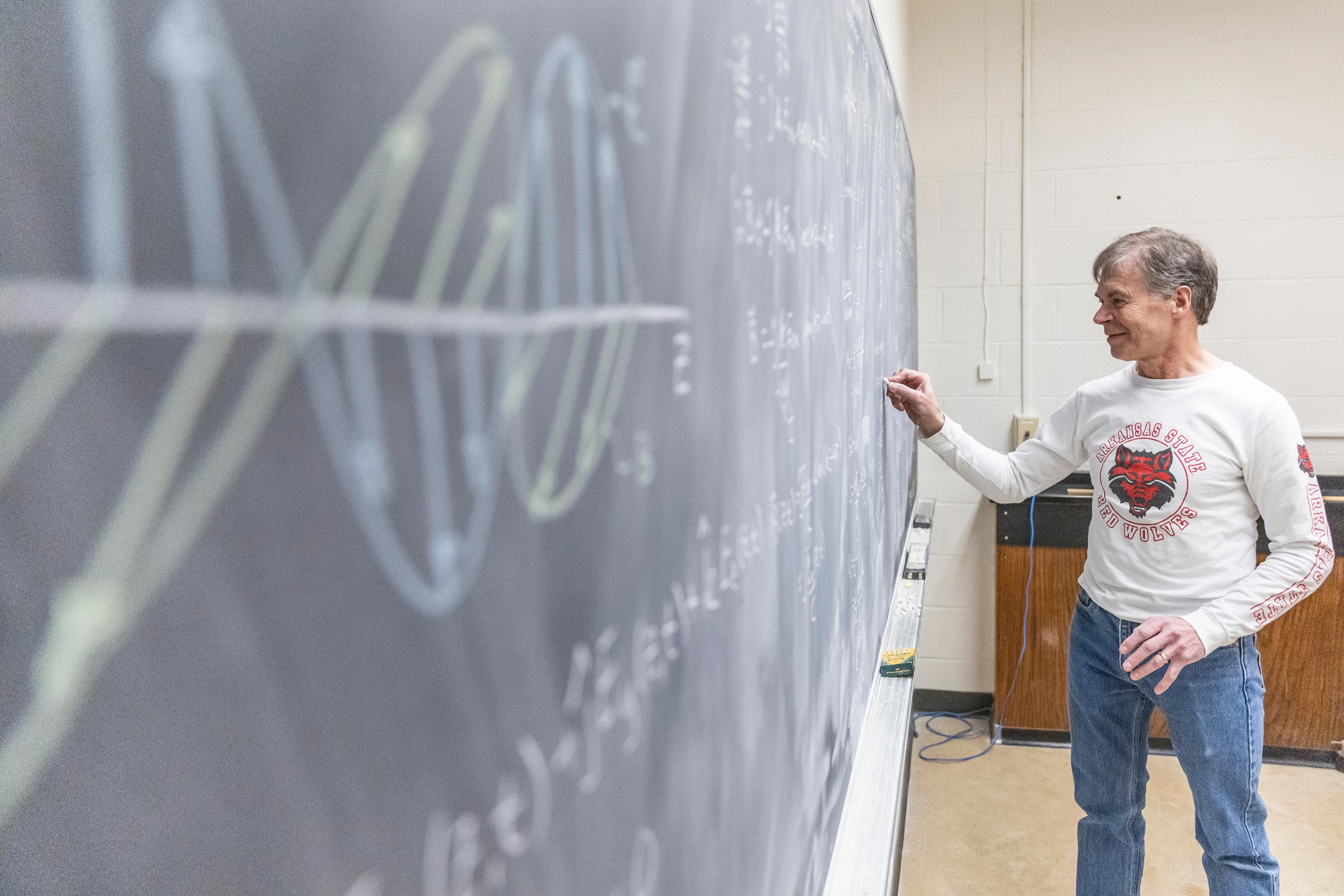 A professor writing equations on a chalkboard.