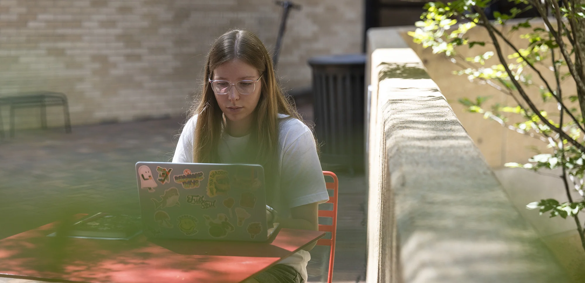 A student working on her laptop outside.