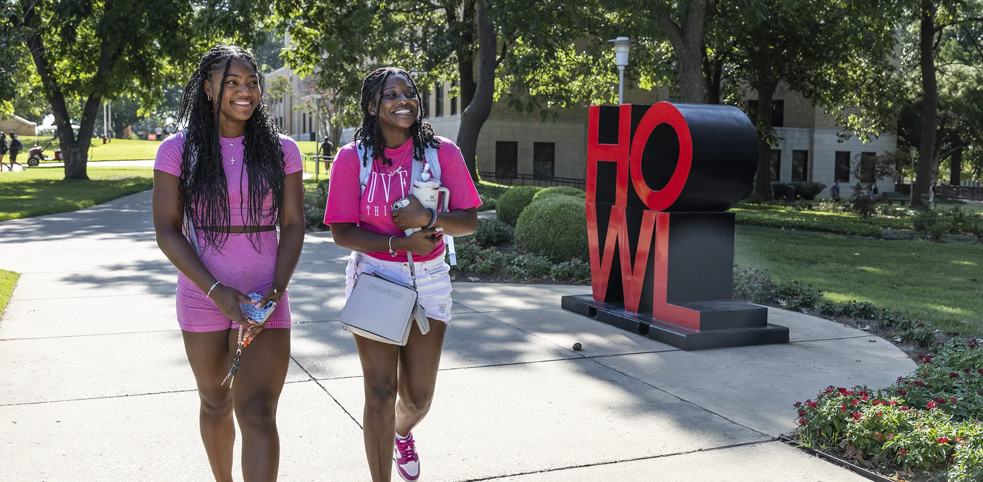 Two students walking by the HOWL sculpture.