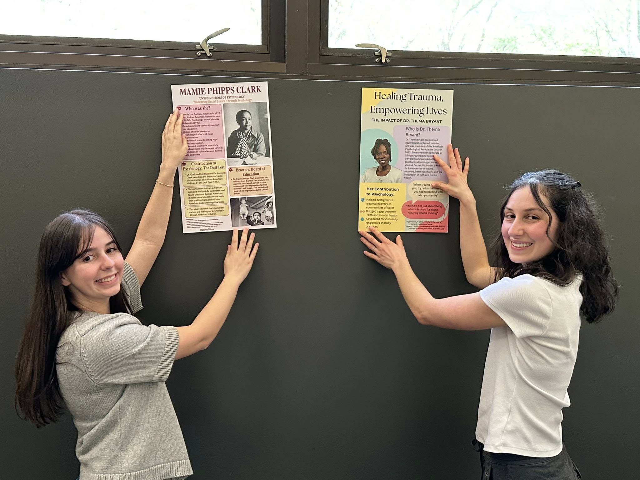 Two students displaying posters they made for "unsung heroes" of psychology.