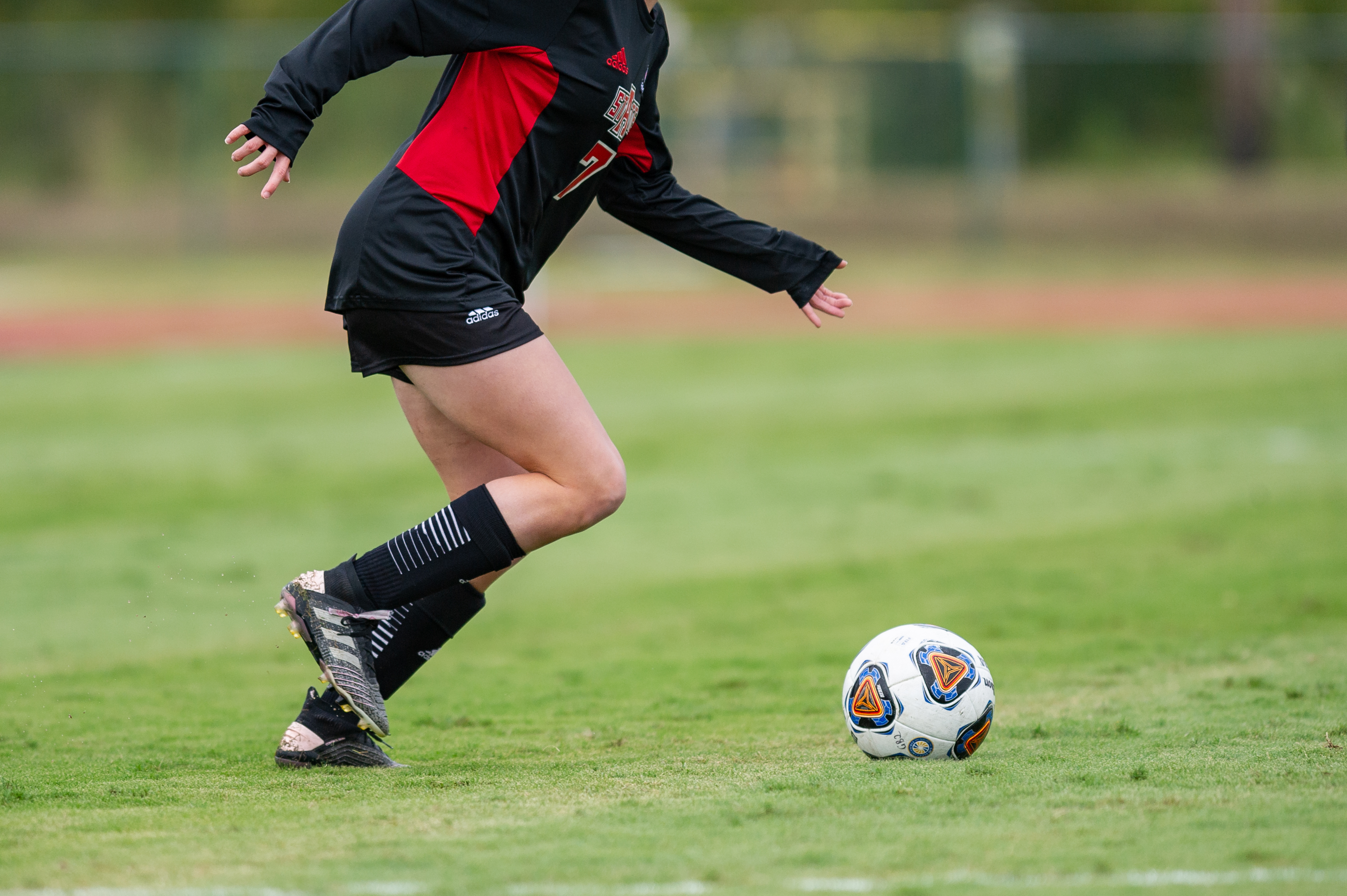 Close-up of a soccer player's legs as they are about to kick a soccer ball.