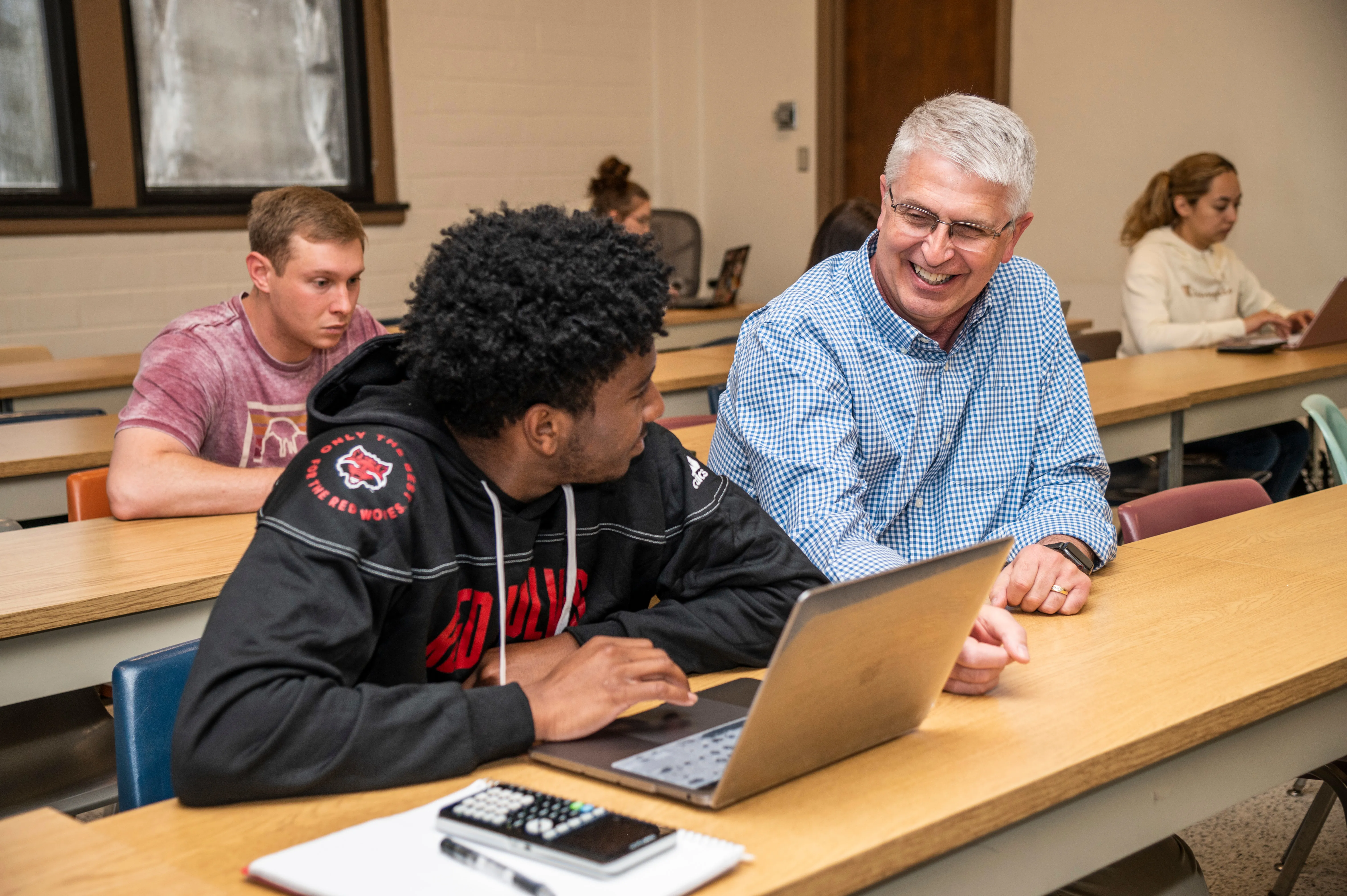 A-State student and teacher sitting in business class working on work together.