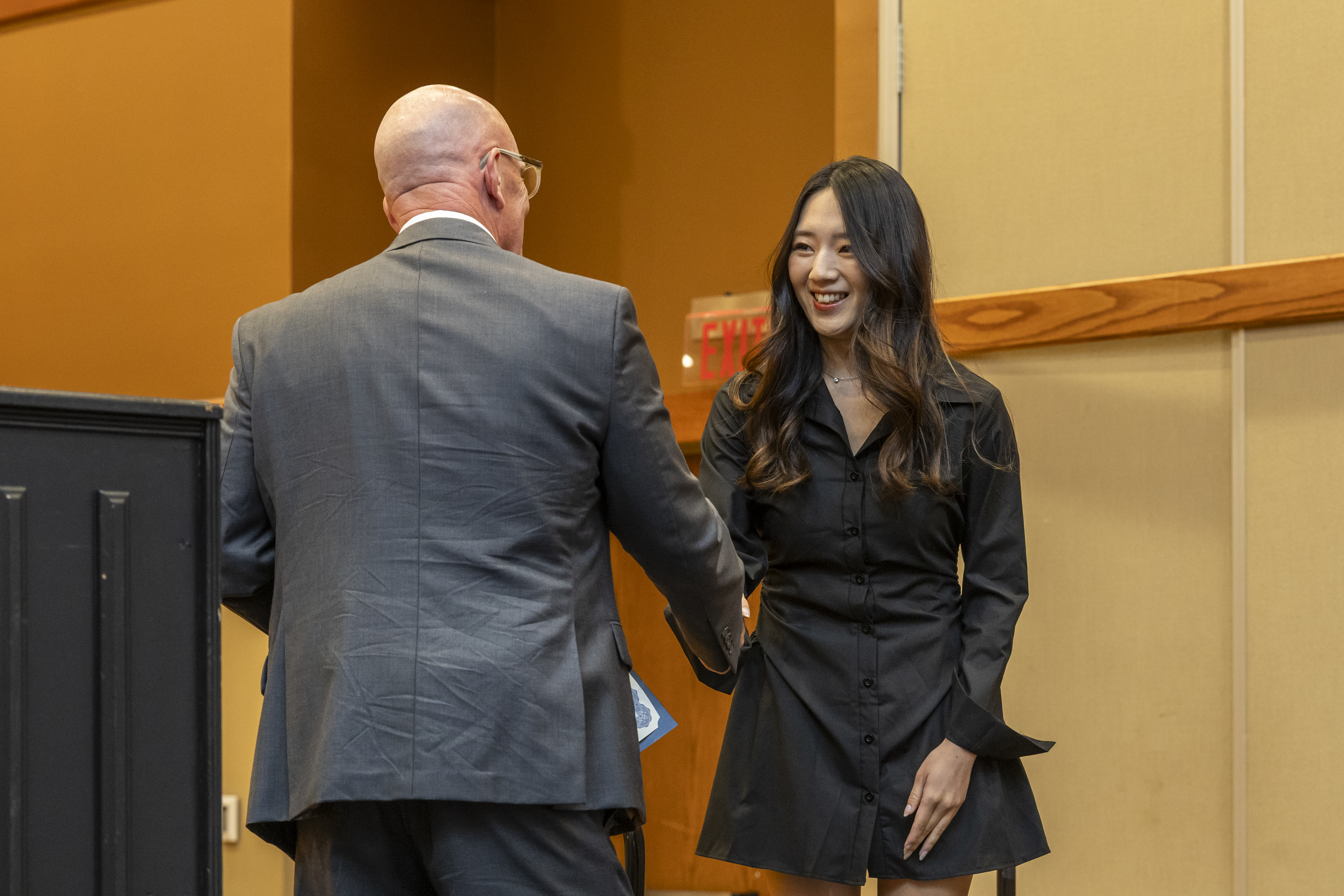 A student in formal wear shaking hands with a man in a suit.