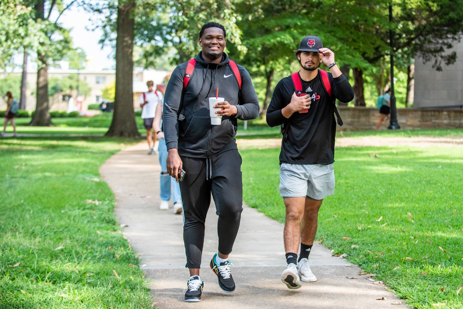 Two students in Red Wolves gear walking on campus.