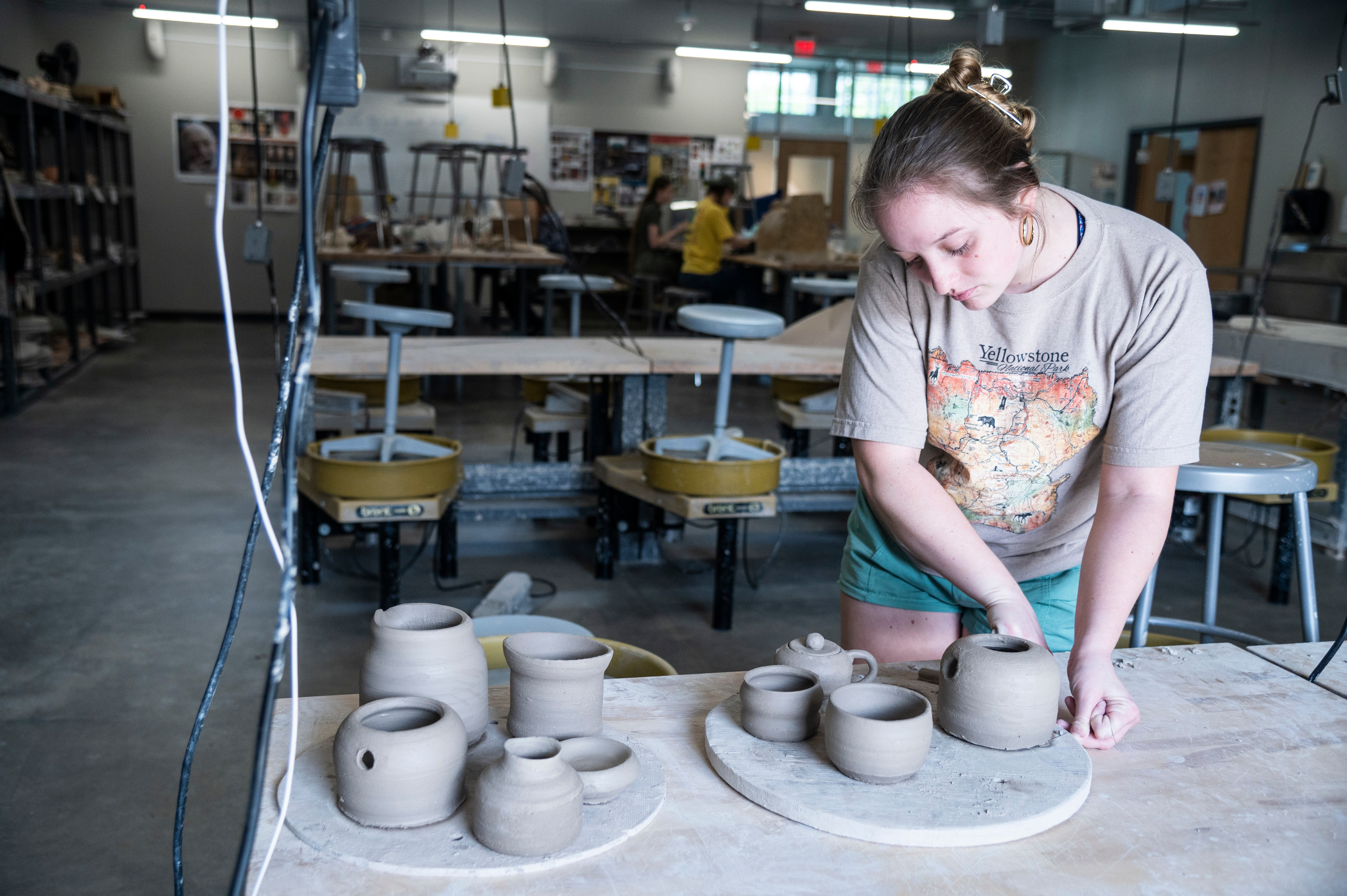 A student creating ceramic pots and cups.