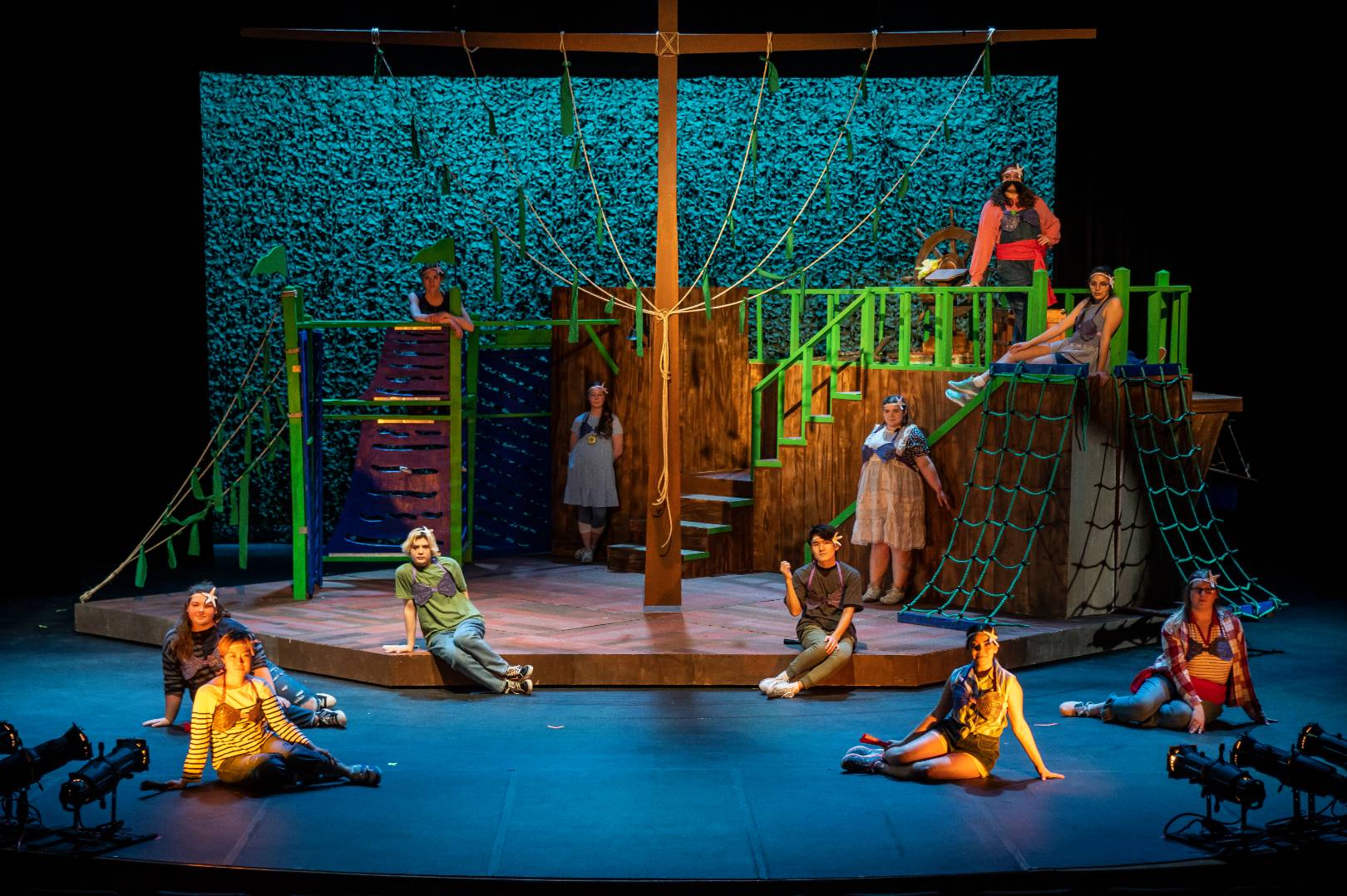 A photo of a stage production, including a pirate ship prop and actors dressed as mermaids.