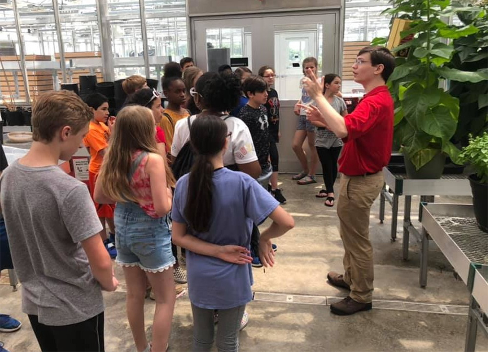 Student leading K-12 students in greenhouse tour