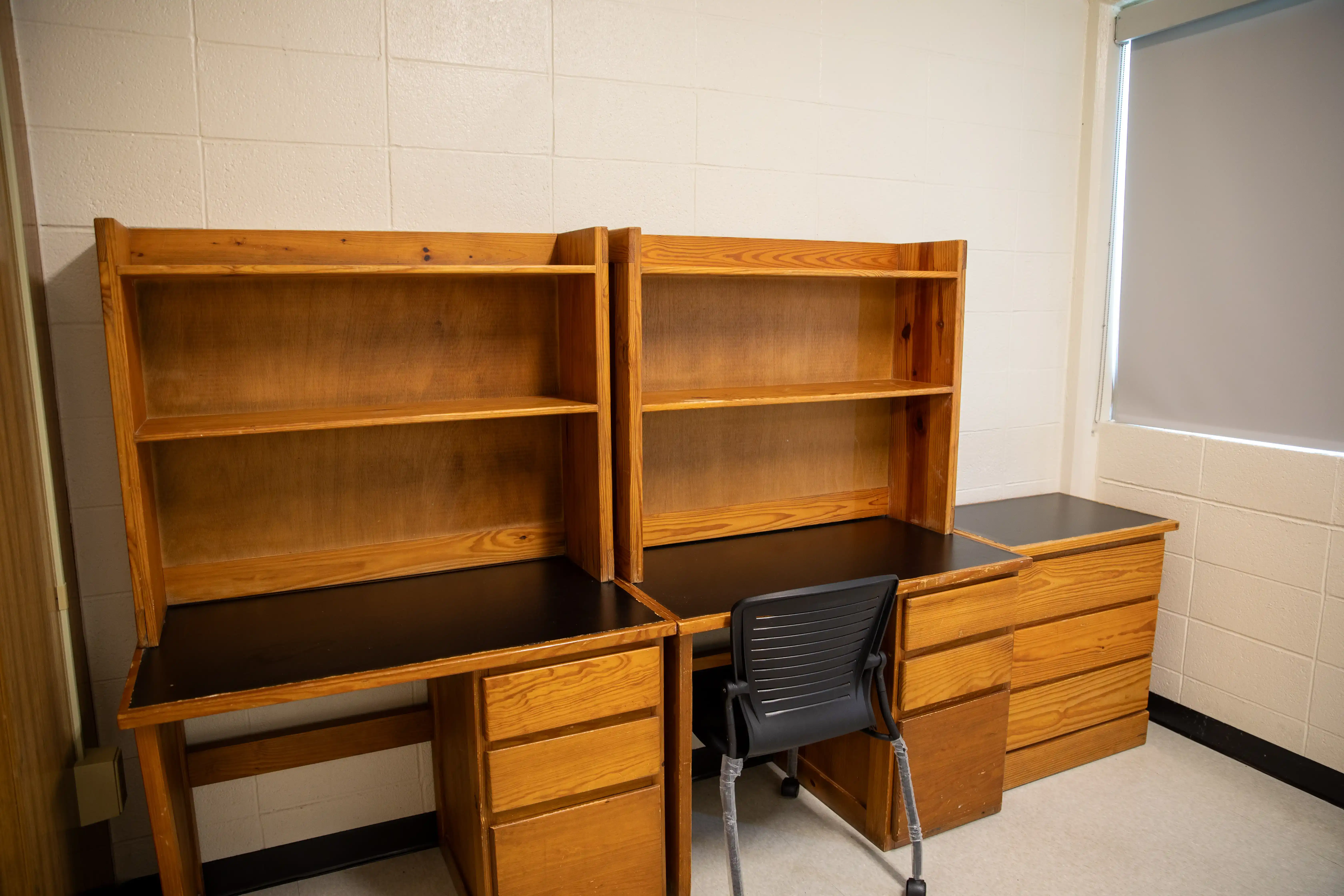 Two desks, a black rolling chair, and small chest of drawers