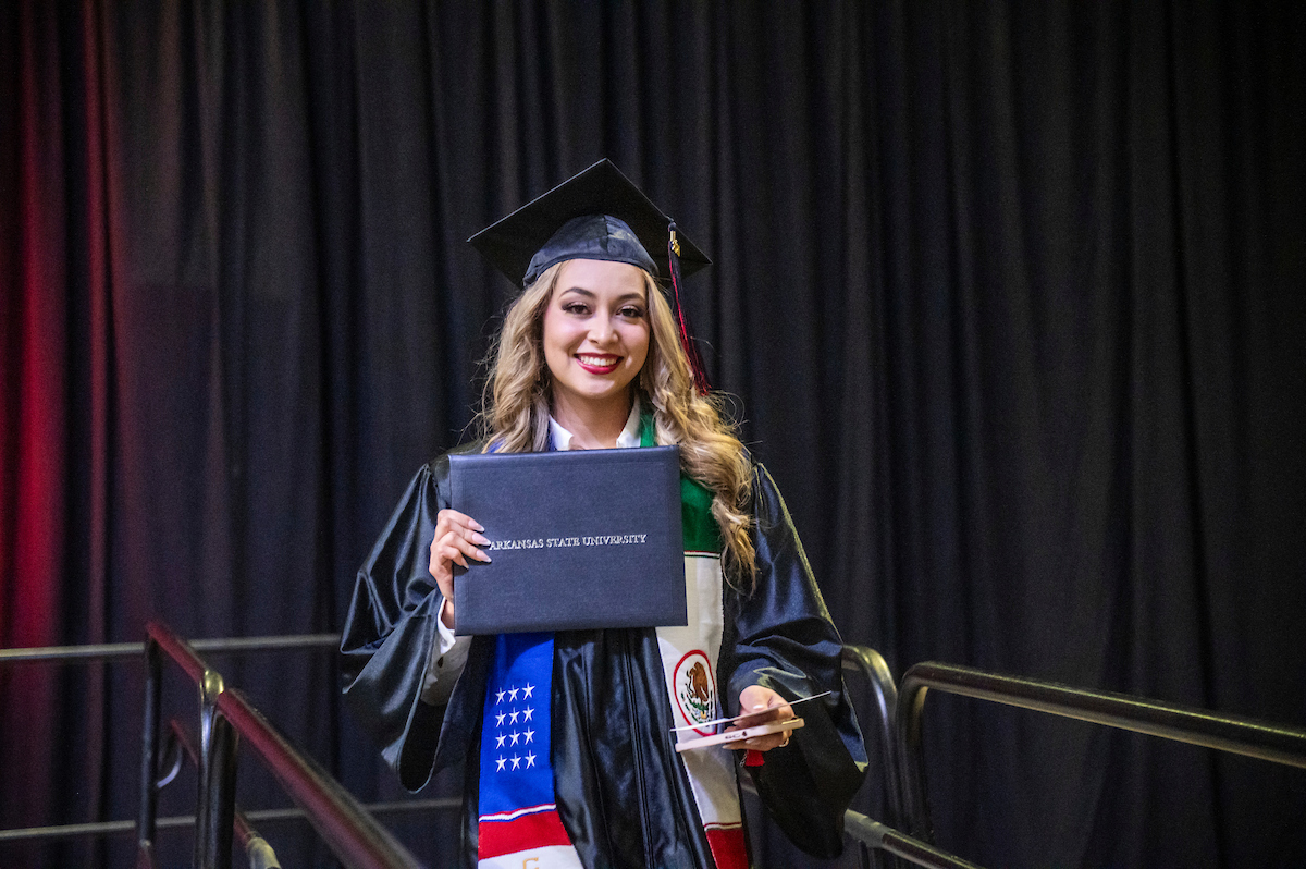 An A-State international student proudly holds her degree during a recent commencement ceremony.