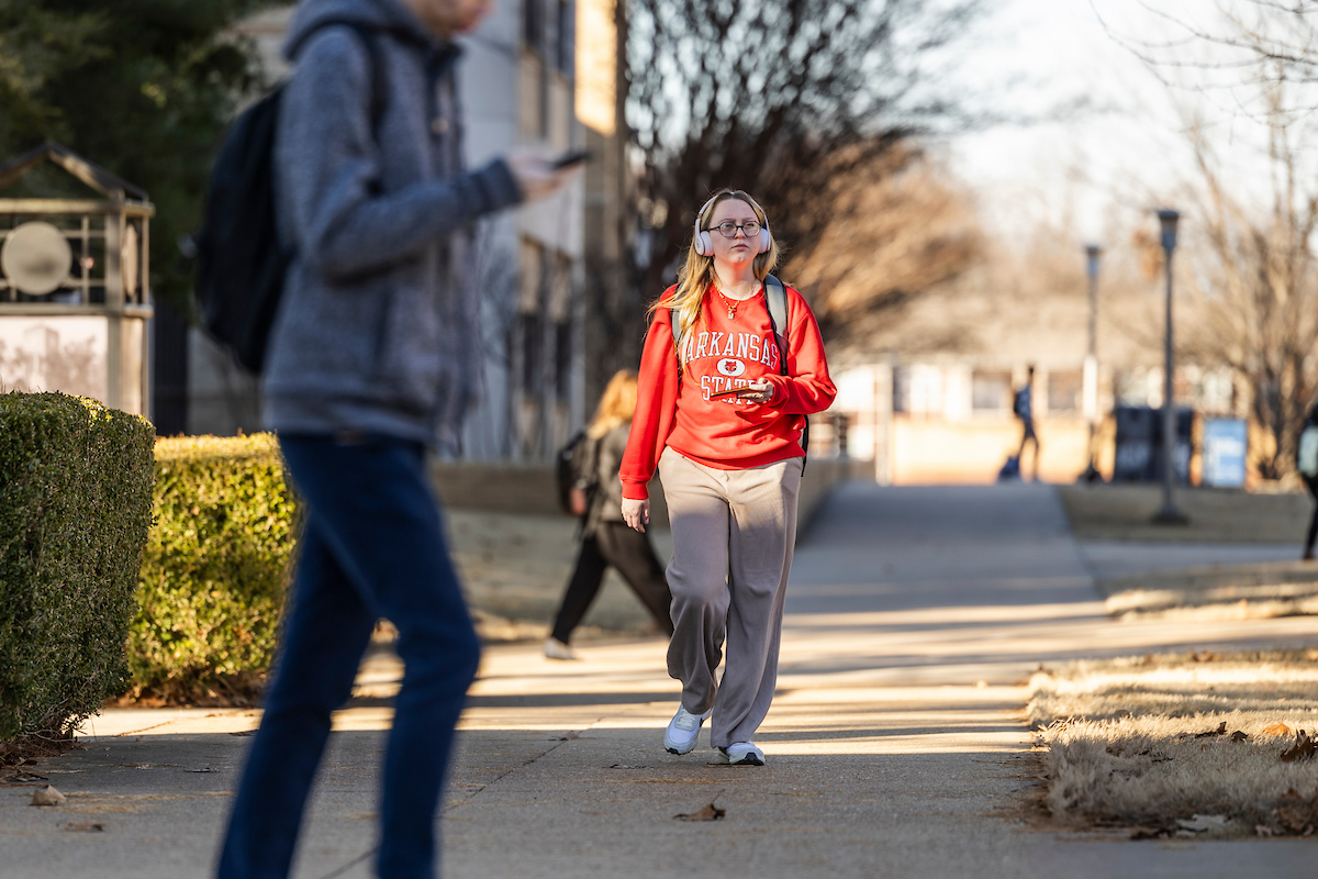 An A-State student walks down the main pathway connecting the library and the Science and Math Building